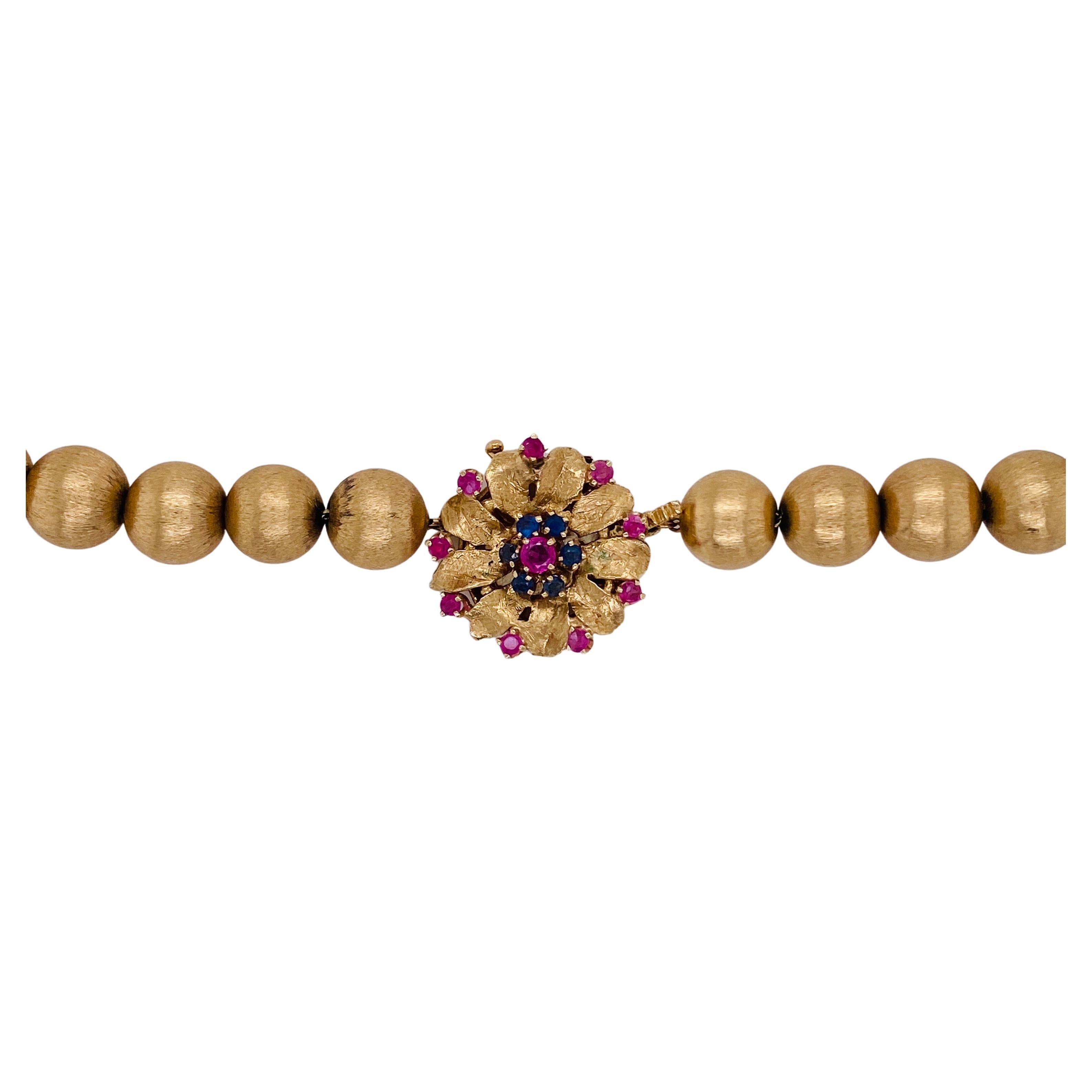 If you want a significant gold necklace, this is the one for you. Beautifully brushed 9 millimeter beads make up the length and there is a gorgeous 19 millimeter diameter gold clasp that is embellished with 9 rubies, 6 sapphires and one larger ruby
