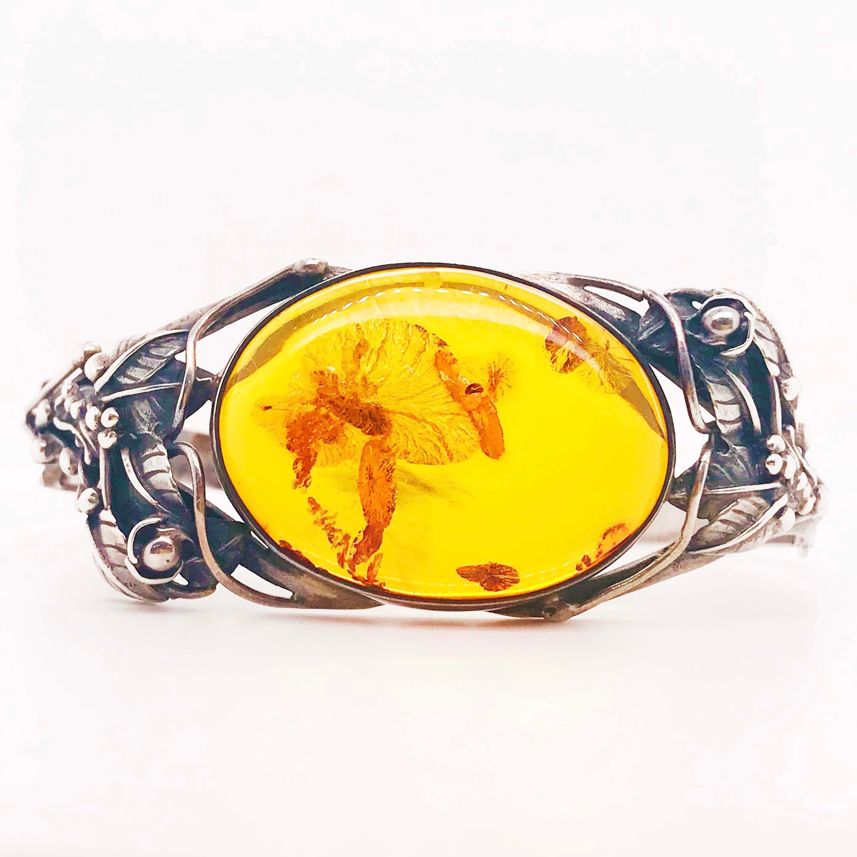 The handcrafted, original sterling silver amber bracelet holds an oval piece of amber gemstone with a history of its own. Amber is resin from ancient pine trees that has been hardened over a long period of time. Inside this amber you can see