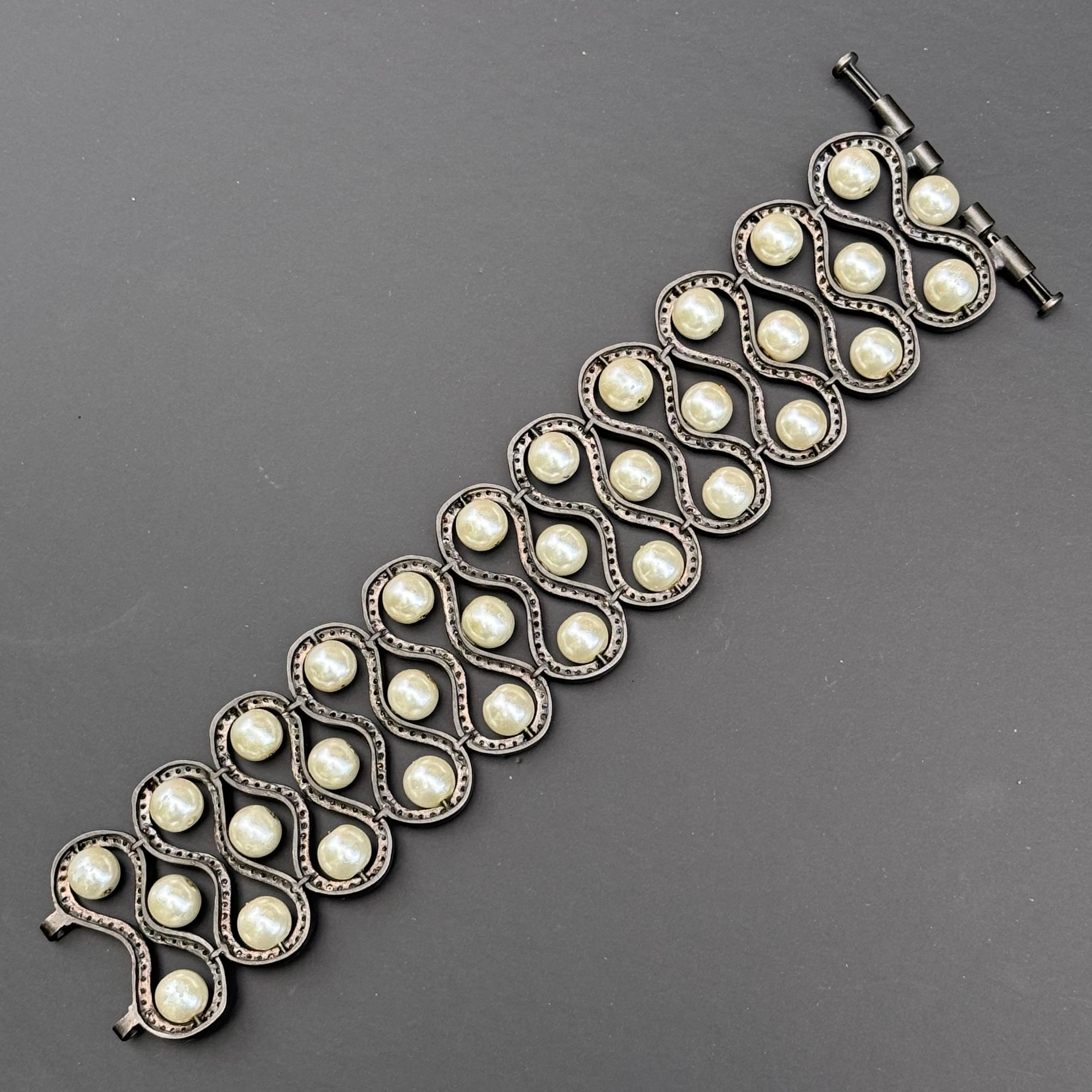 Mod modern bracelet is a handmade masterpiece, likely crafted in India. Featuring eleven diamond-paved panels with faux pearls, it exudes contemporary elegance. Despite missing one tiny diamond and showing light wear on the faux pearls, it's in