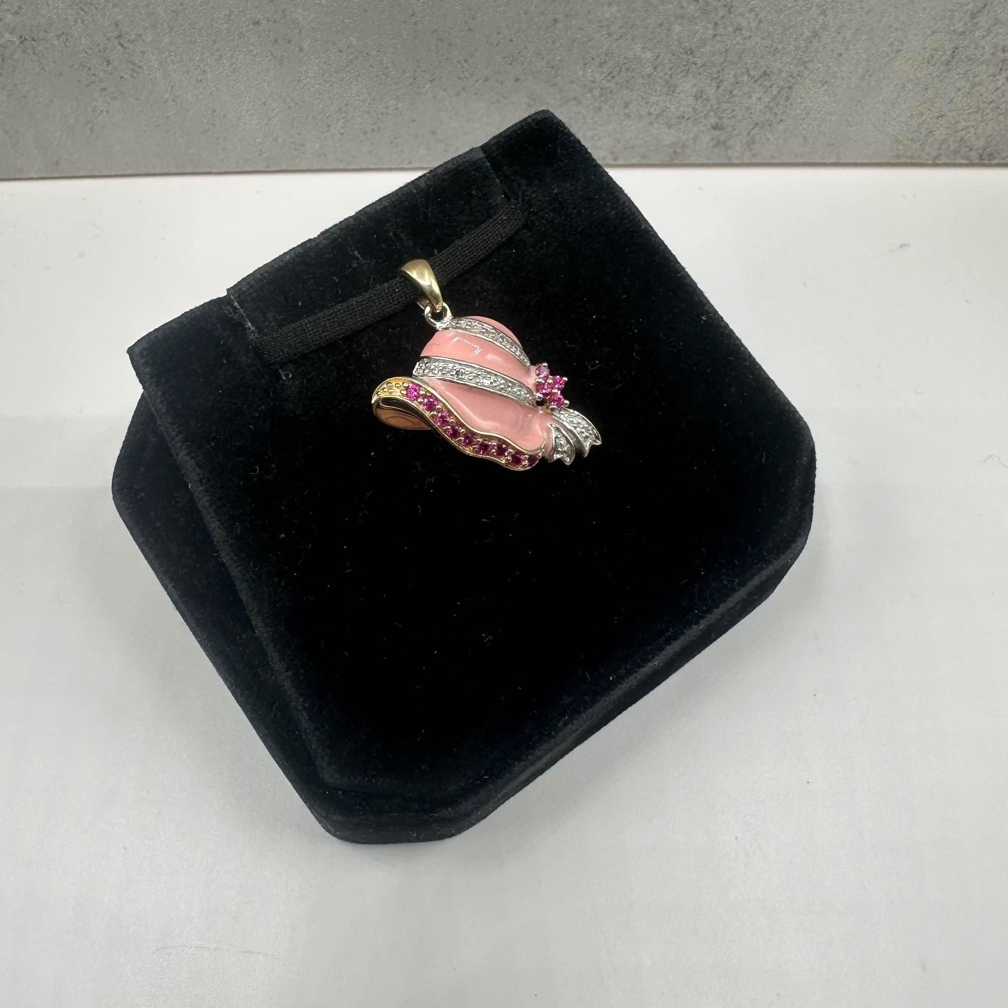 This charming Estate Hat Pendant in 10kt yellow gold features 0.08ctw of round pink rubies and 0.02ctw of natural HI I1 round single-cut diamonds for added sparkle. The pendant also showcases vibrant pink enamel and white rhodium around the diamonds