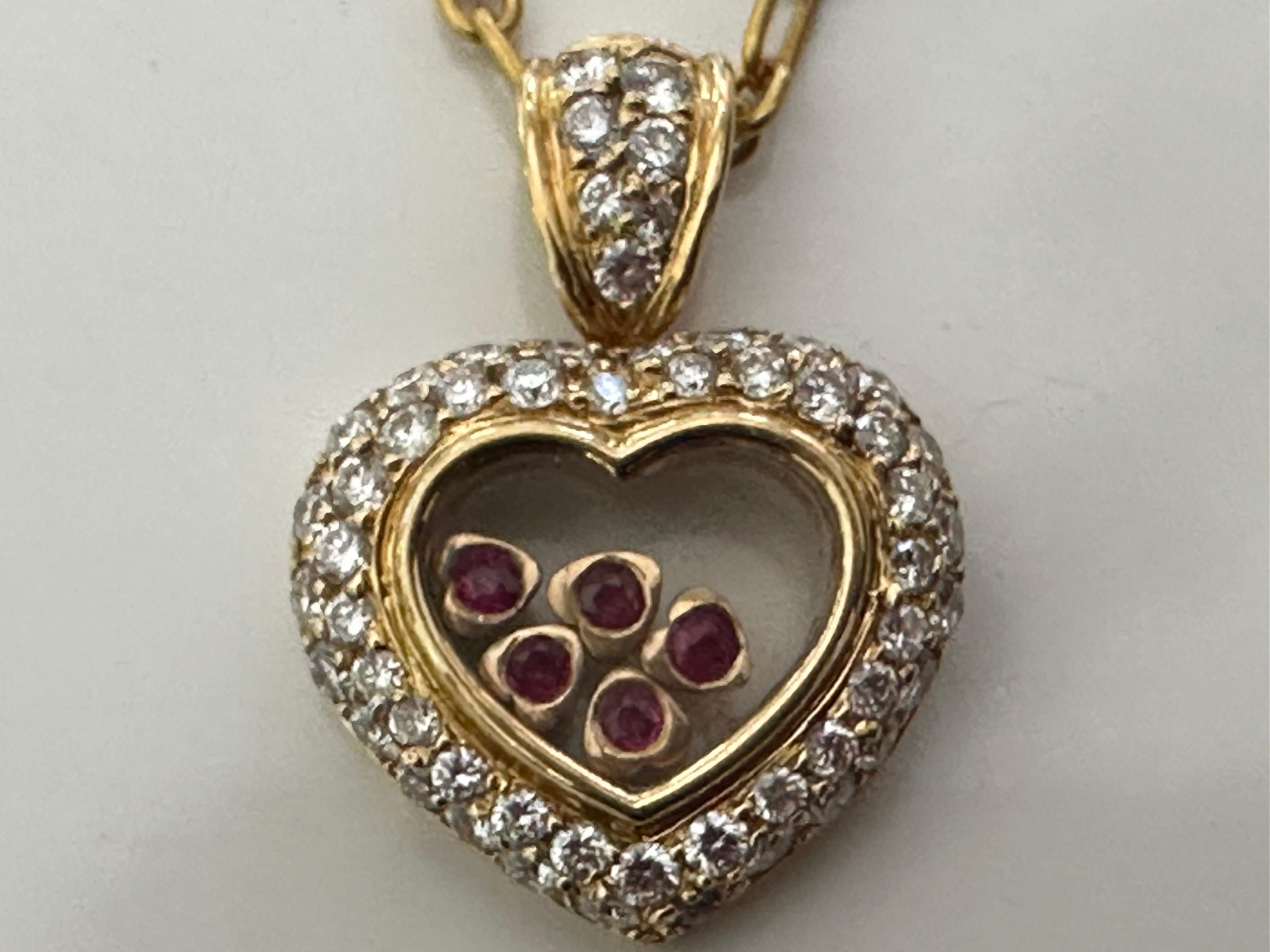 This heart-shaped pendant crafted in 18K yellow gold features approximately 1.30 carats of glistening round brilliant-cut diamonds, F color, VS clarity and five red rubies floating inside the heart (inspired by Chopard's Happy Hearts collection).
