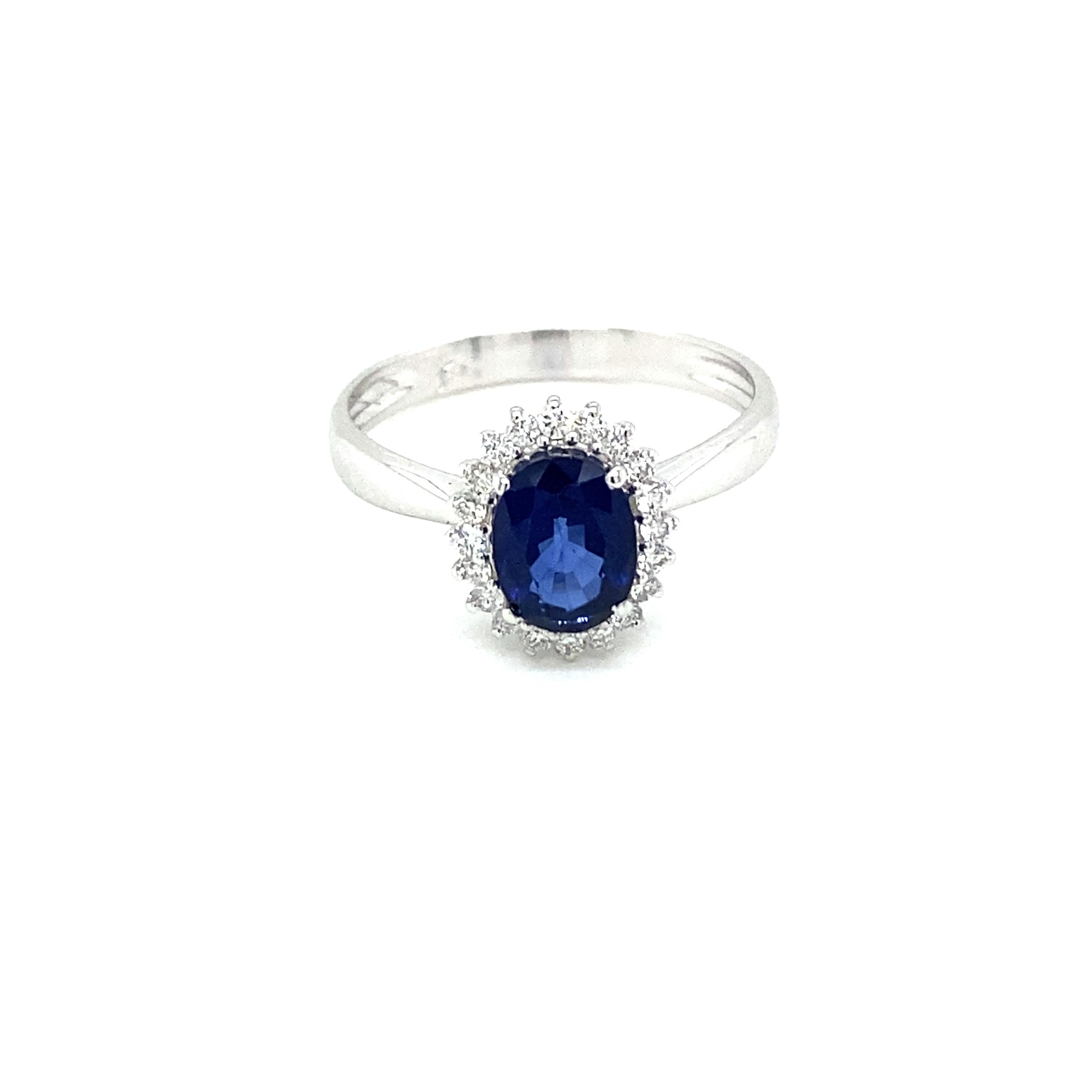 Elegant 18k white Gold, Sapphire and Diamond cluster Ring.

It is set in the center with a Bright oval-cut Natural Sapphire weighing 1,40 carats of extraordinary color and clarity, flanked by sparkling Round Brilliant cut diamonds weighing 0,20