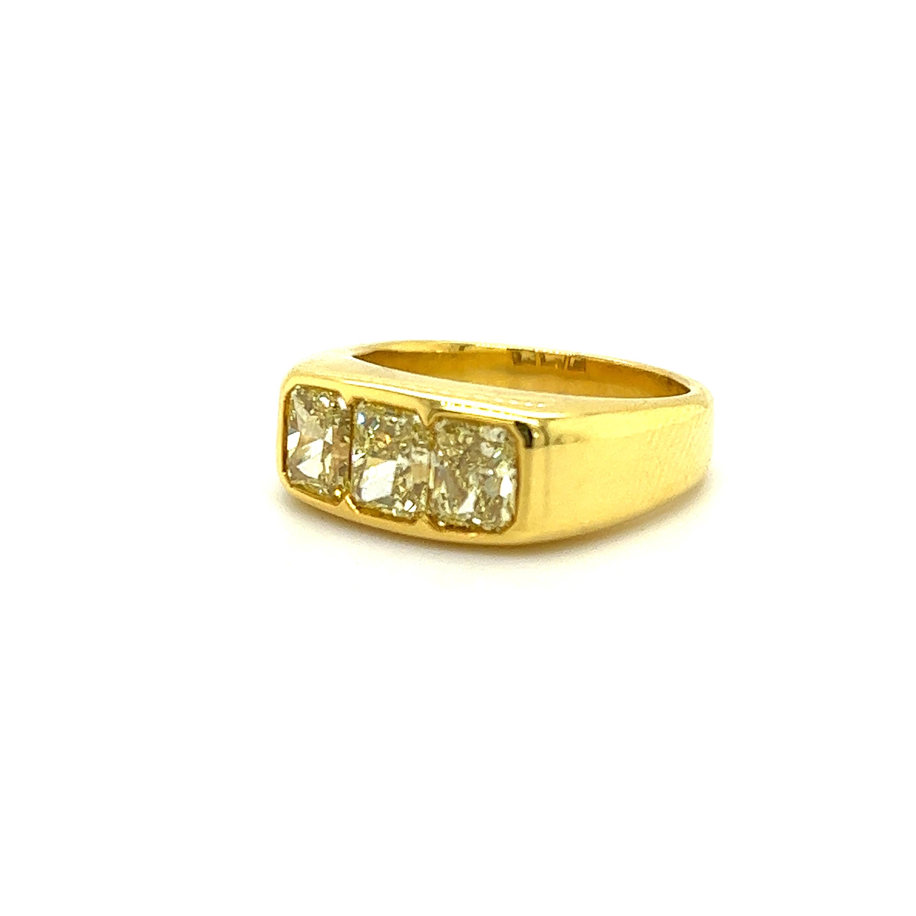Exceptional ring crafted in 18 yellow gold. The ring highlights three fancy yellow colored earth mined natural diamonds. The diamonds are radiant cut and show a vibrant yellow color. Each diamond weighs 1.00 carat and are matched perfectly. The ring