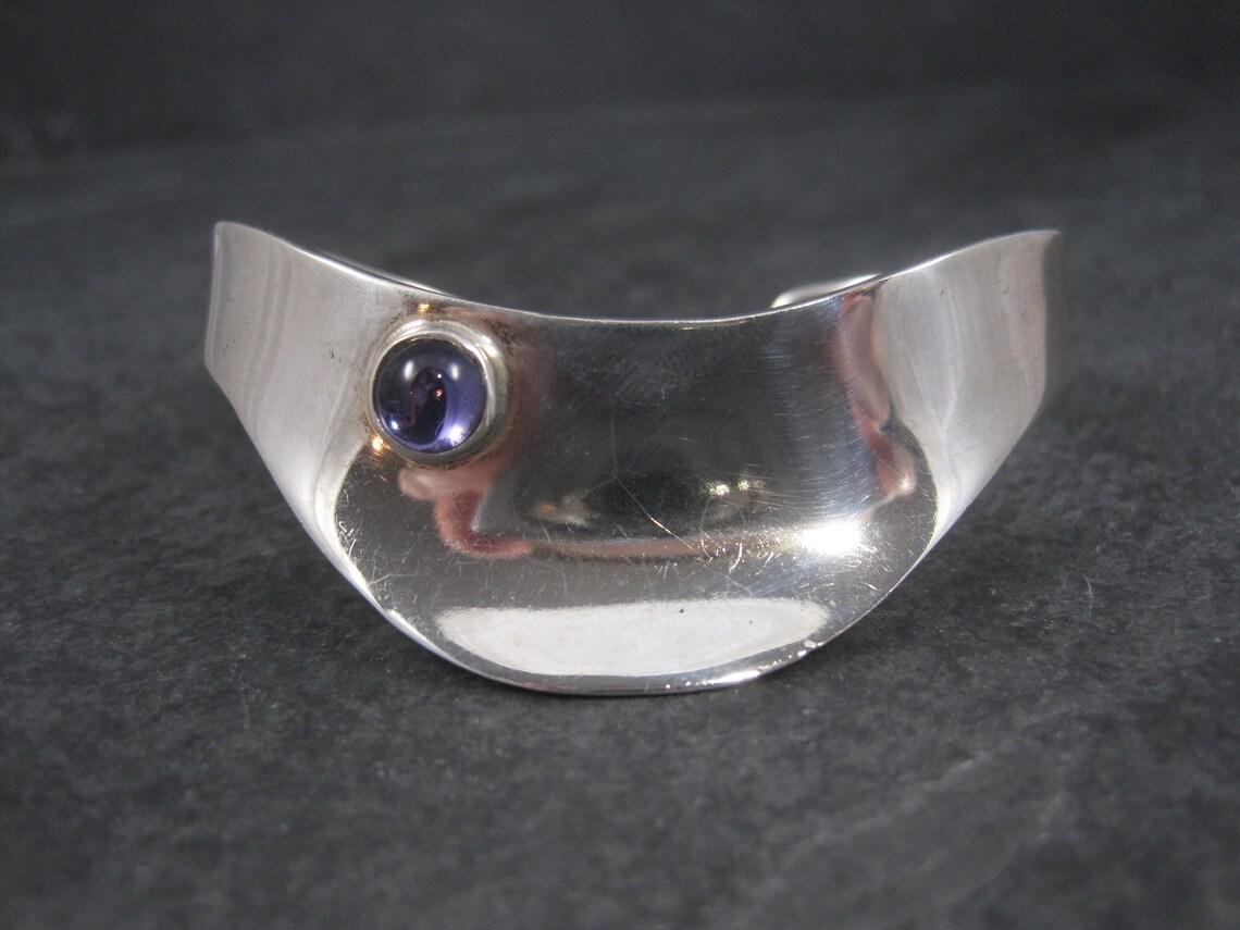 This gorgeous vintage Mexican cuff bracelet is sterling silver.
It features a 7mm amethyst gemstone.

The face of this bracelet measures 7/8 of an inch and tapers down to 3/8 of an inch.
It has an inner circumference of 6 inches, including the 1