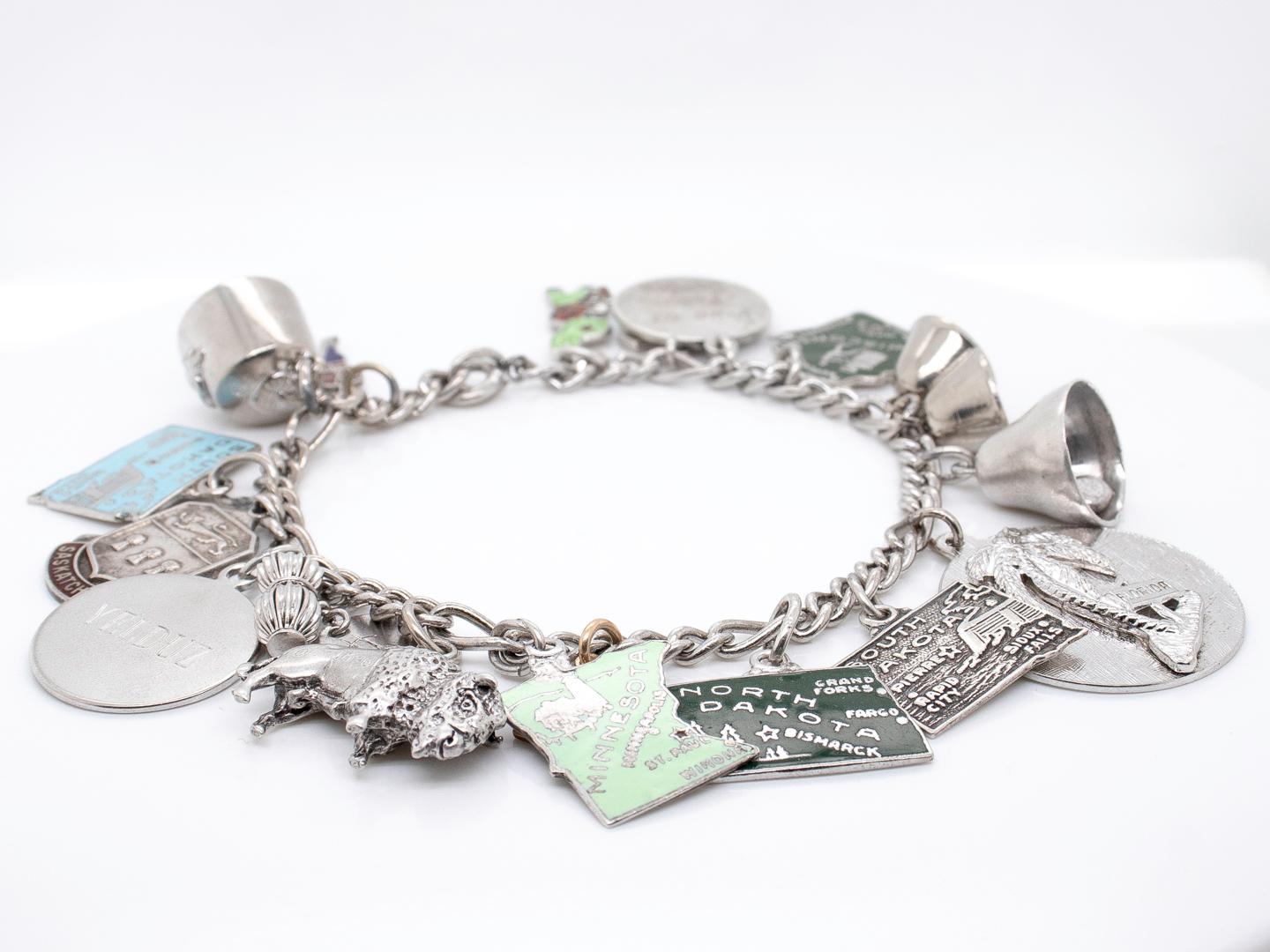 A fine Mid-Century charm bracelet.

In sterling silver.

Including 17 charms that among others include a 3-dimensional buffalo, a money bag, a Palm tree for Florida, bells, a Freemason's hat, an enameled rabbit, an enameled Canadian Mountie, and