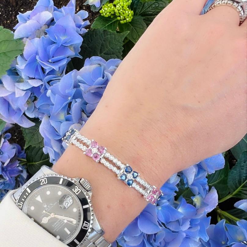 Designed in 18k white gold, this unique and elegant bracelet satisfies the pink and blue lover alike! With two rows of 101 round brilliant diamonds, weighing a total of 2.61 carats, G-H-I/VS quality, and accented with nine 'florets' of alternating