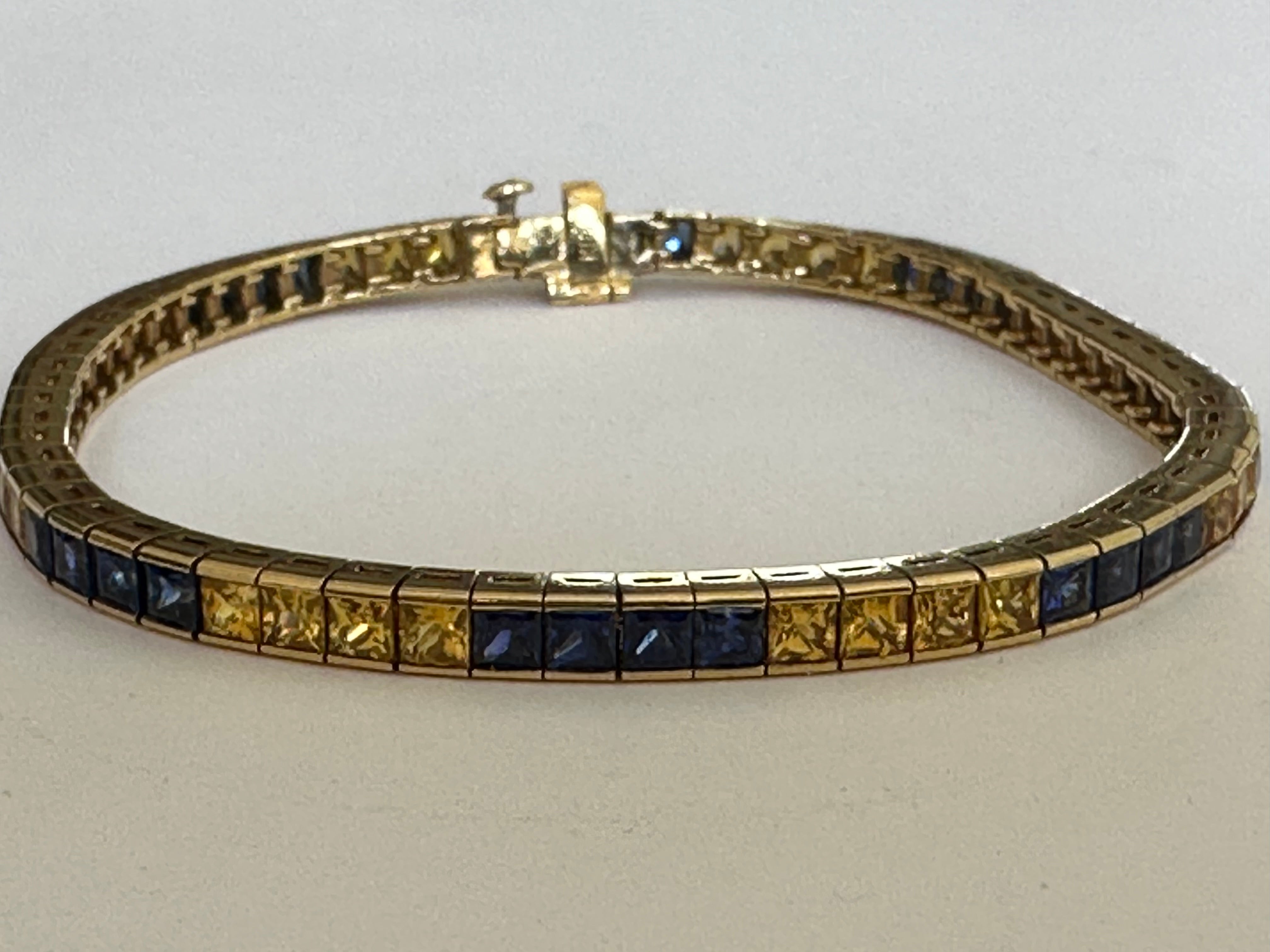 Crafted in 18k yellow gold, this stunning estate link bracelet features alternating rows of natural blue and yellow square cut sapphires totaling approximately 7.50 carats. The bracelet measures 7 inches. 