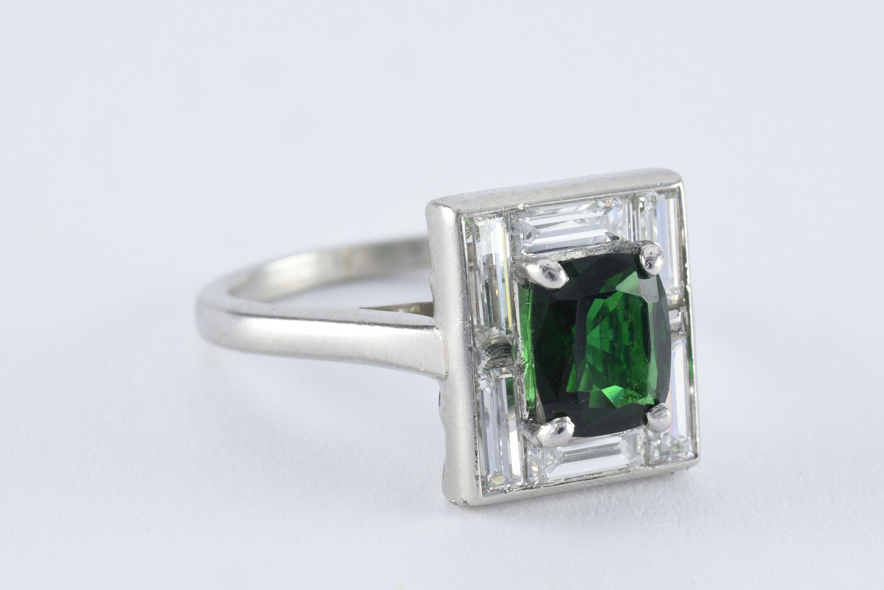 This estate cocktail ring is designed around a natural green cushion-cut chrome tourmaline measuring 7.3mm x 6.3mm and totaling approximately 1.41 carats bordered by six baguette-cut diamonds totaling approximately 1.00 carats, F-G color, VS clarity