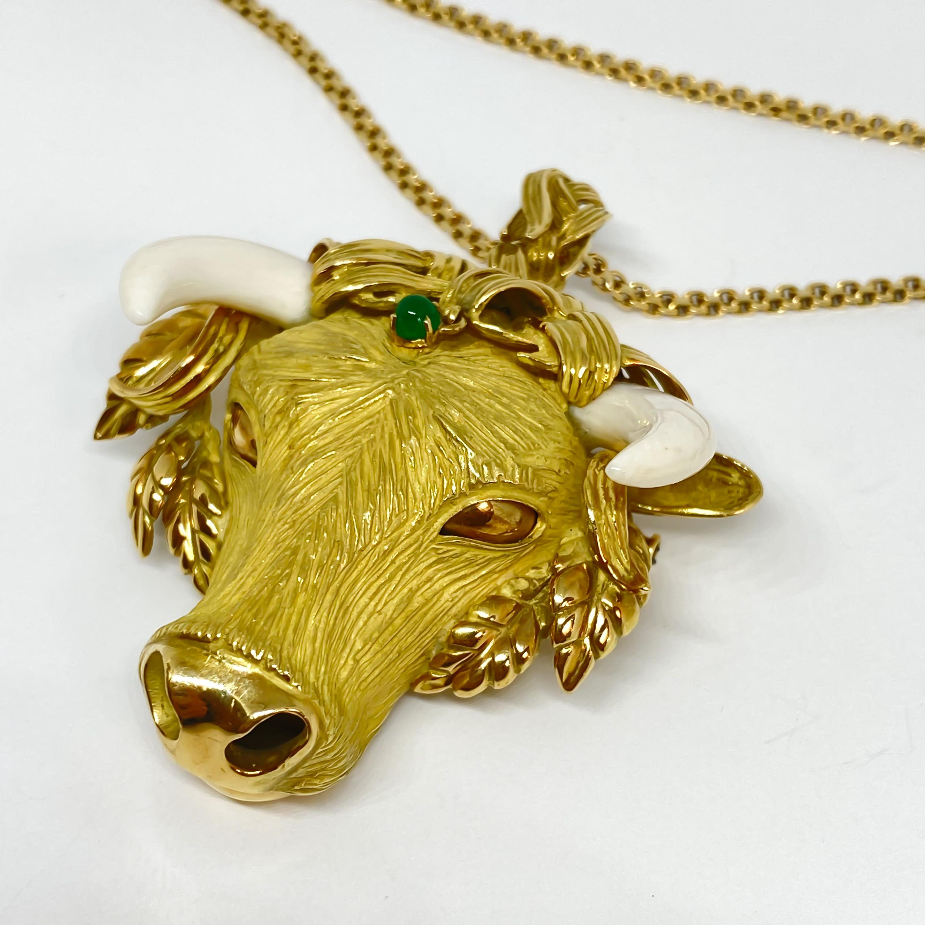 Very exquisite Bull pendant that converts into a brooch is designed in 18 karat yellow gold. The estate piece has natural ivory horns and emerald dangle from headdress. It is enhanced by beautiful polished leaves, polished nose and eyes. The head is