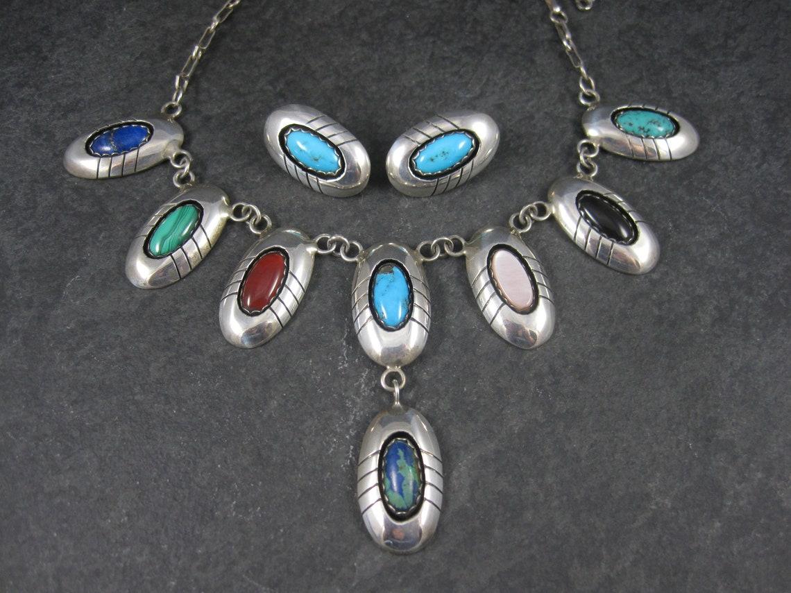 This gorgeous Navajo jewelry set is sterling silver.
It features natural turquoise from 2 different mines, lapis lazuli, malachite, carnelian, pink mother of pearl, onyx and azurite set within shadowbox settings.

The earrings measure 5/16 by 1 1/16