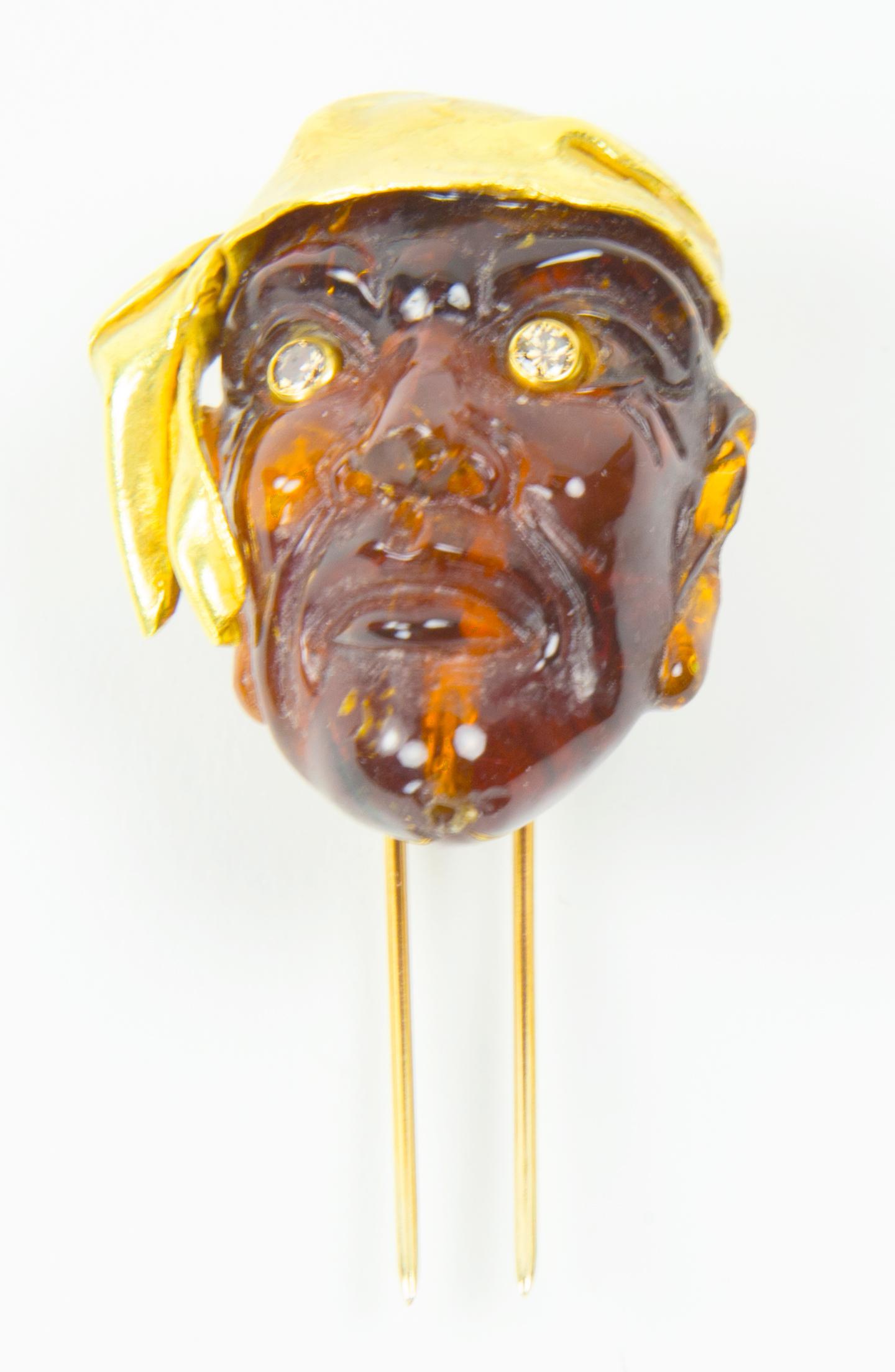 Sensational Finely detailed Antique Natural Amber Gemstone Figural Mask Pin, featuring a Pirate with Champagne Diamond set eyes and wearing a 22 Karat Gold Hand crafted Headdress; Hand Carved in 3D with exquisite detail and attention for quality.