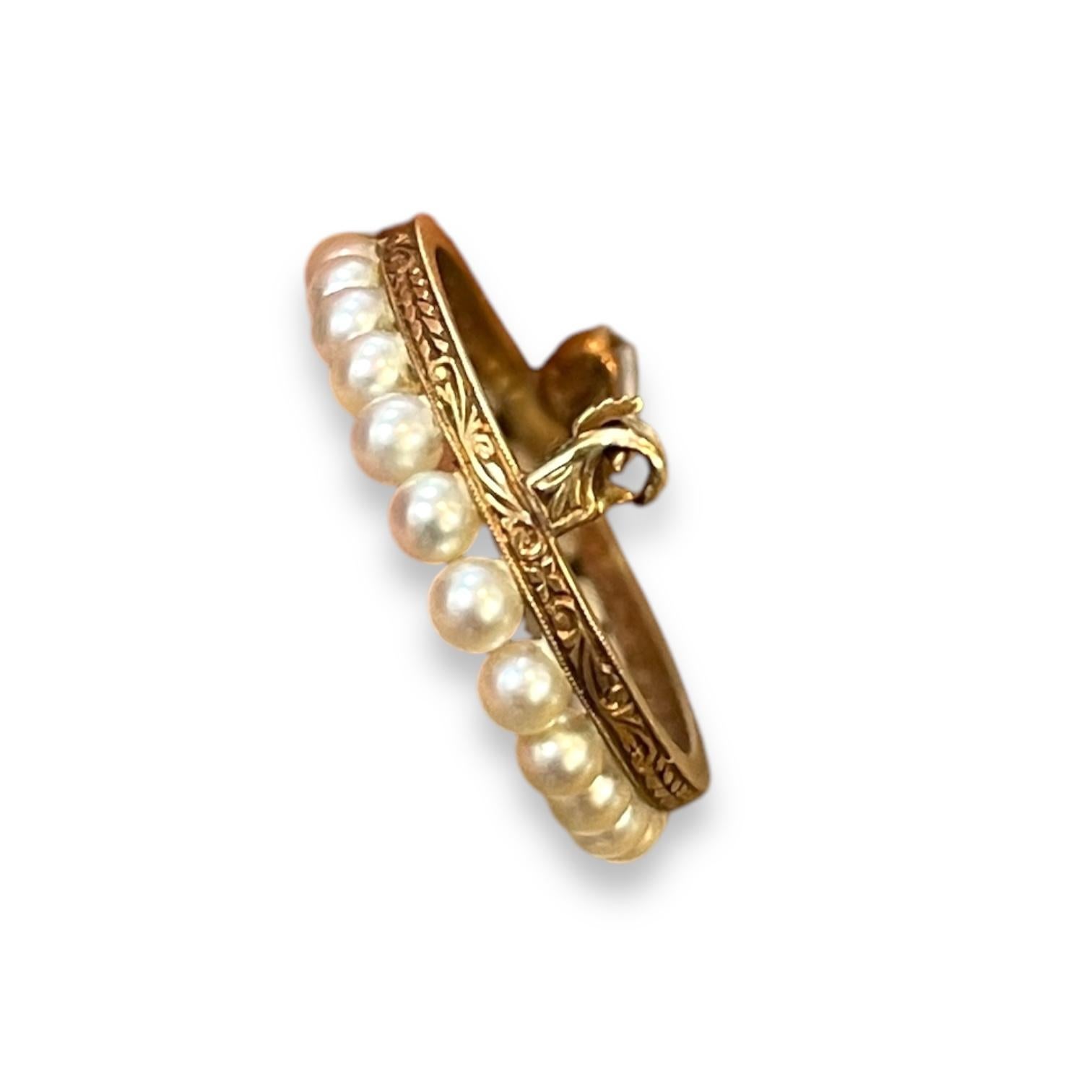 Une broche élégante composée d'un délicat arrangement de perles lustrées, serties dans une forme ovale gracieuse. Les perles sont méticuleusement alignées le long d'une fine monture en or, créant un look raffiné et sophistiqué. Cette pièce est un