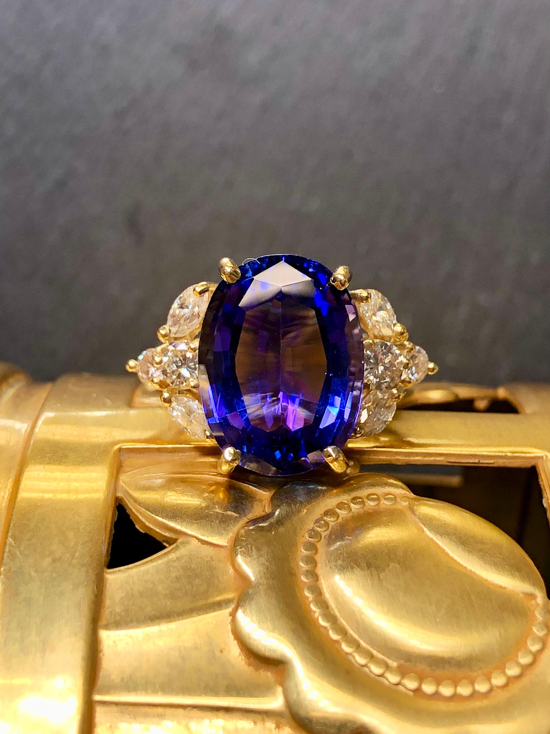 
A classic vintage cocktail ring done in 18K yellow gold centered with an approximately 7.50ct oval tanzanite exhibiting a beautiful violet blue hue. Flanking the center stone are larger marquise and round diamonds being H-J color and Vs1-2 clarity