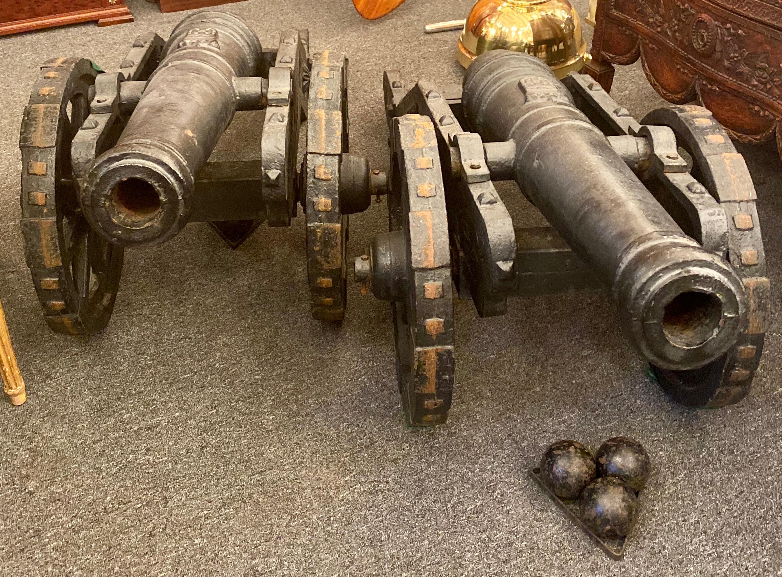 Estate 20th century pair of cast iron reproduction 19th century American cannons and caissons. Includes two sets of three matching cannonballs and their accompanying stands. Cannons are exclusively for decorative use. Wheels function and cannon can