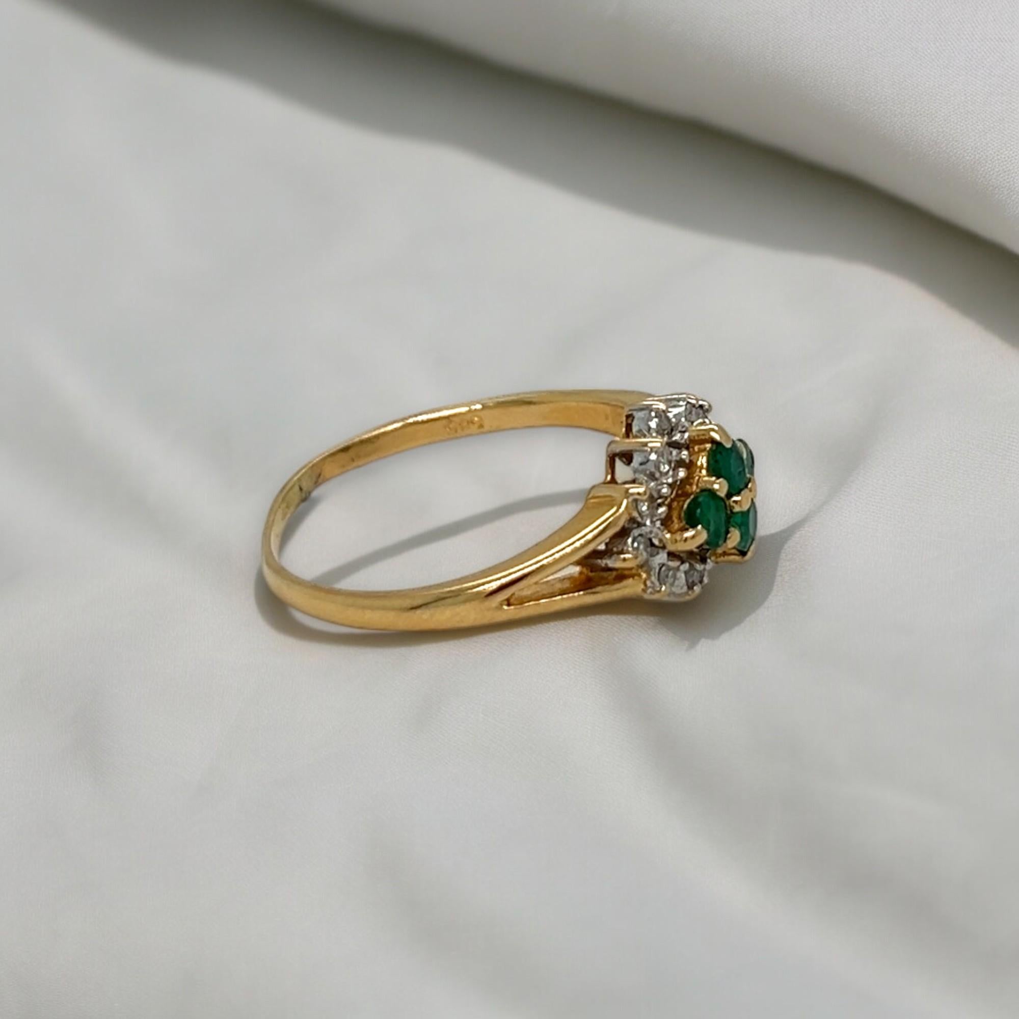 Estate piece: This cluster ring features 0.32 total carats of round diamonds and 0.12 total carats of round emeralds. Set in 14k yellow gold. Ring can be sized upon purchase.