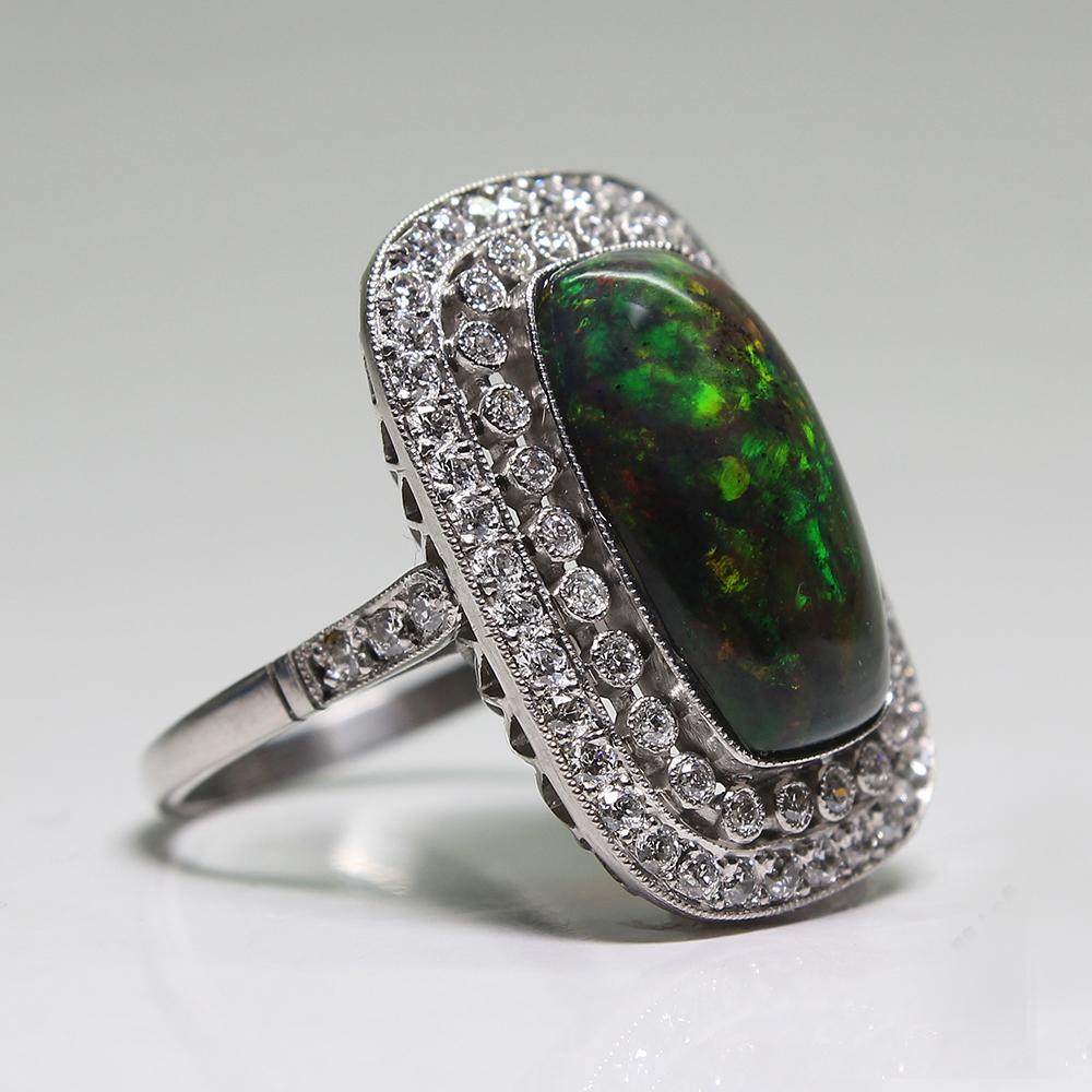 Period: Estate 
Composition: Platinum

Stones:
•	1 natural black opal that weighs 3.60ctw. and measures 16mm by 9mm
•	70 Old mine cut diamonds of H-VS2 quality that weigh 1.10ctw.
Ring size: 6 ½    
Ring face:  23mm by 17mm 
Rise above finger: