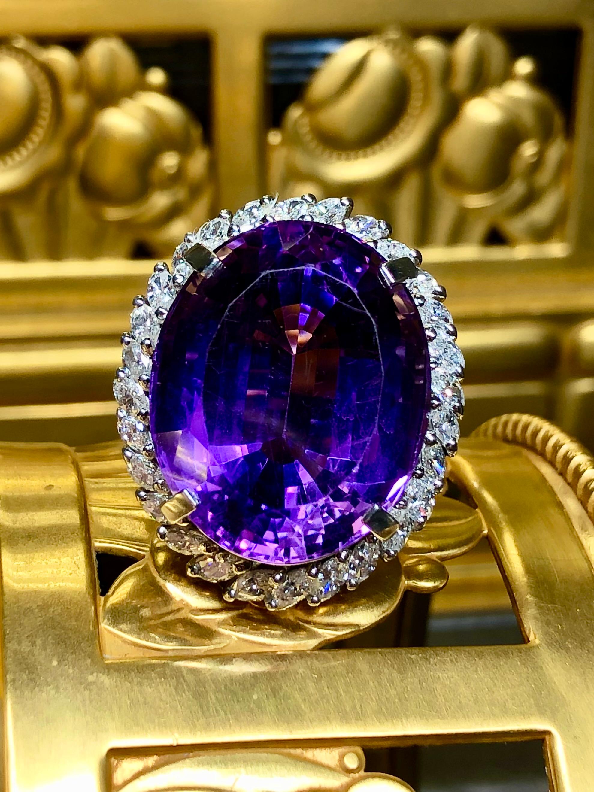 A bold and beautiful large cocktail ring crafted in platinum and centered by a 33.97ct natural amethyst surrounded by approximately 2.03cttw in G-H color Vs1-2 clarity larger marquise diamonds. The front and back of the setting is also artistically