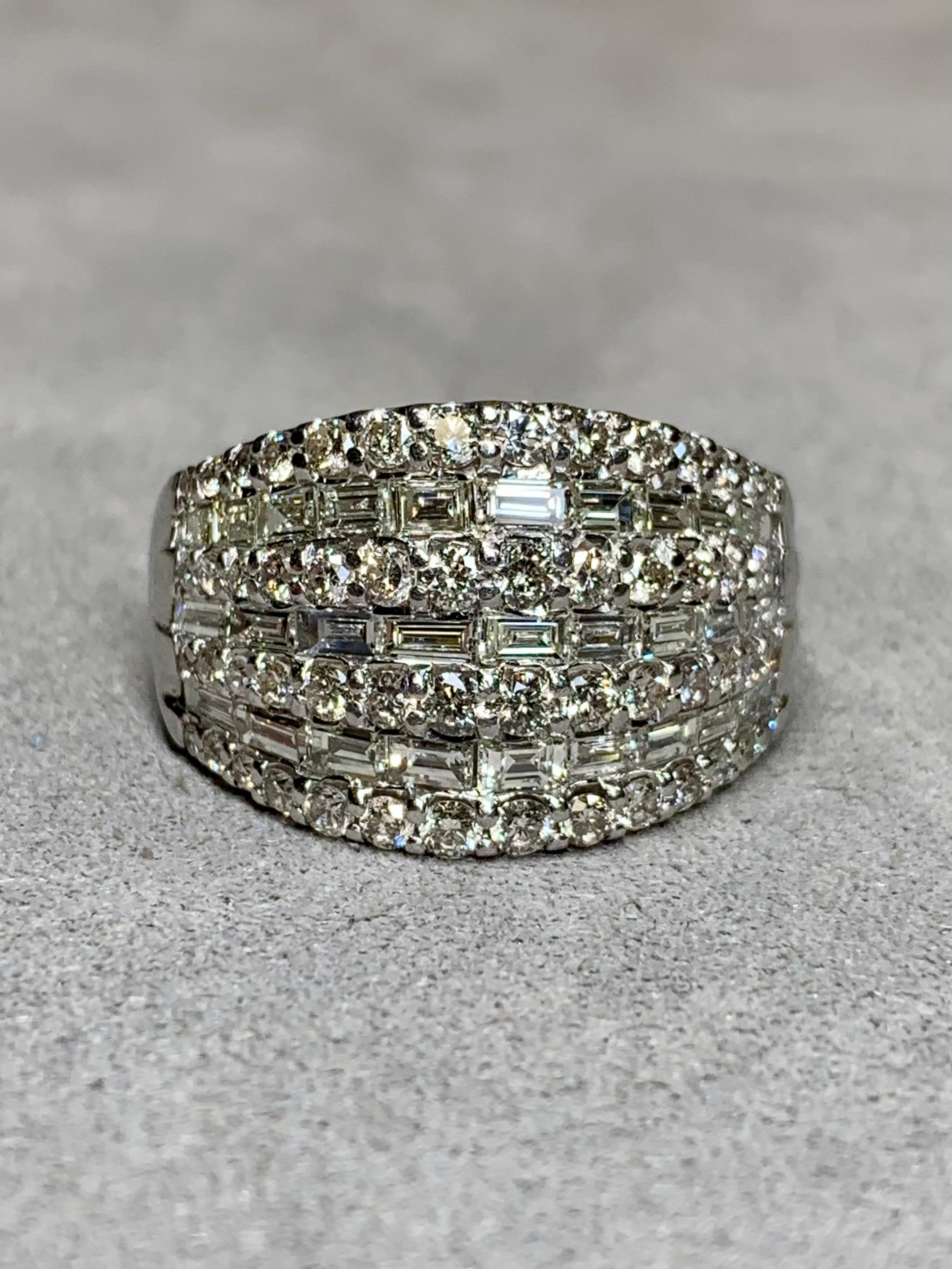 
An elegant wide cocktail ring done in platinum and set with approximately 2.60ctw in both baguette as well as round diamonds. All round diamonds average H-J in color and Si1-2 in clarity and H-J in color. The baguettes are matching in color and