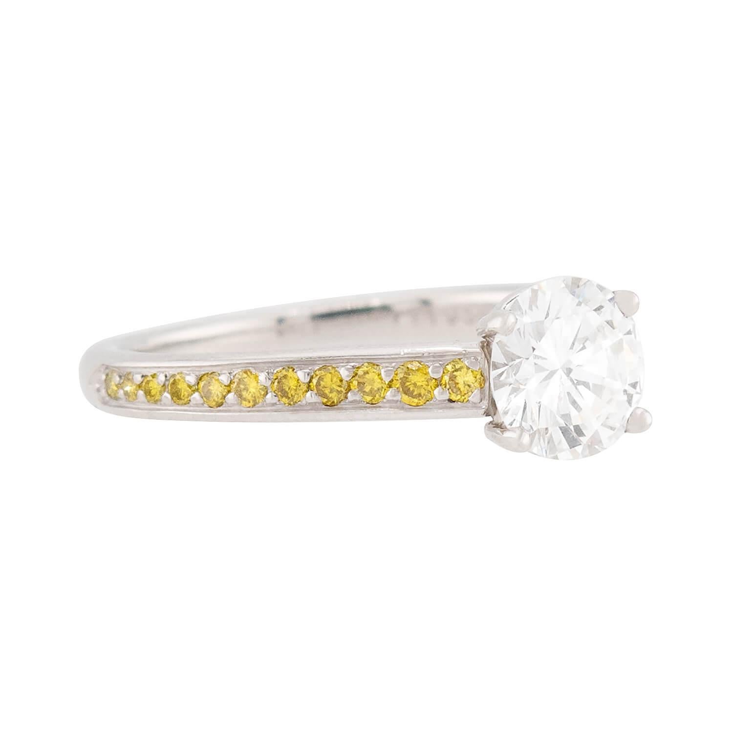 Une bague de fiançailles en diamant d'une beauté classique ! Réalisée en platine, cette bague est ornée d'un diamant central moderne de taille ronde et brillante, serti dans une monture à quatre griffes et pesant 1,03 carat. La pierre est de couleur
