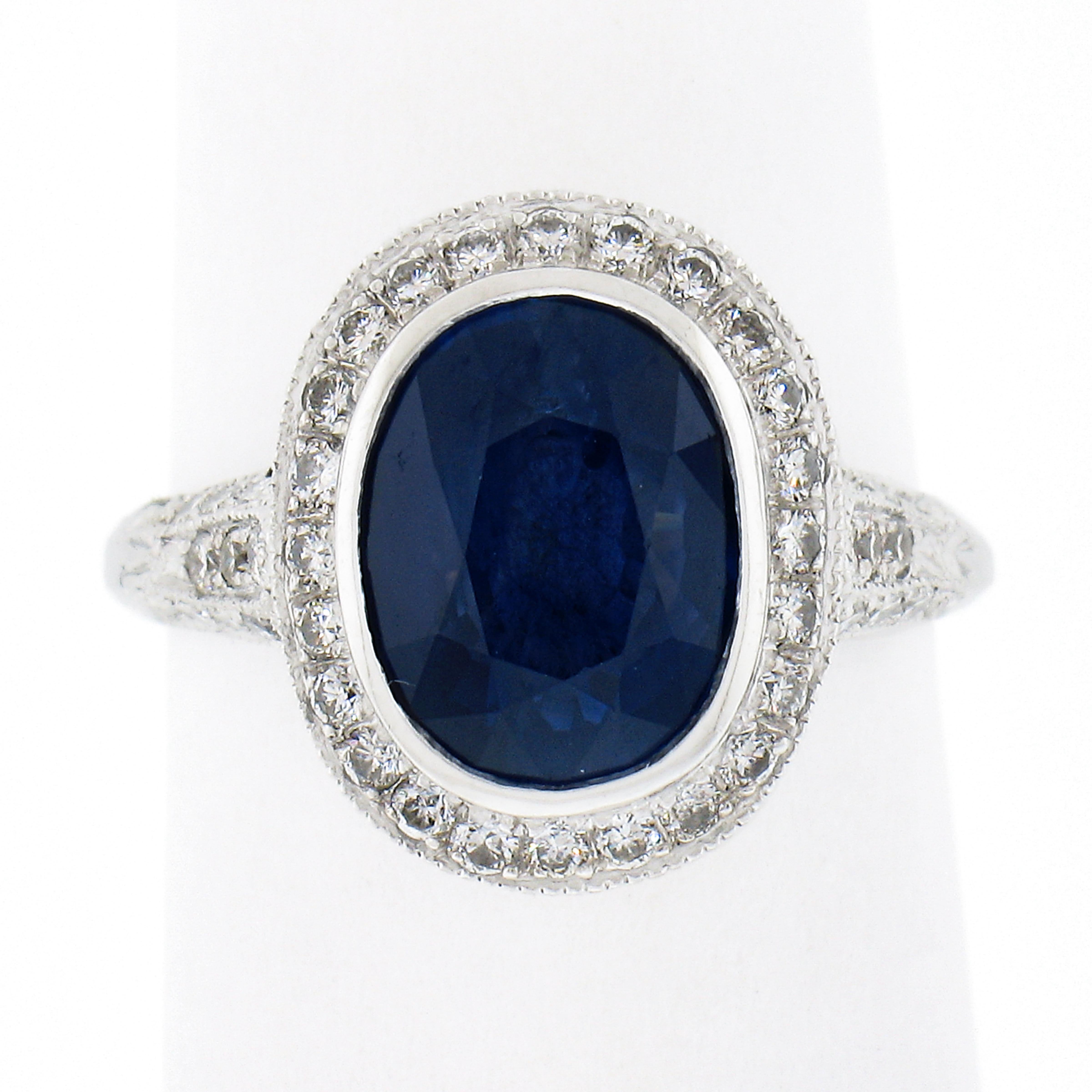 This stunning sapphire and diamond ring is crafted in solid platinum and features a beautiful, GIA certified, natural genuine sapphire neatly bezel set at the center of a raised diamond halo design. This oval brilliant cut sapphire has an attractive