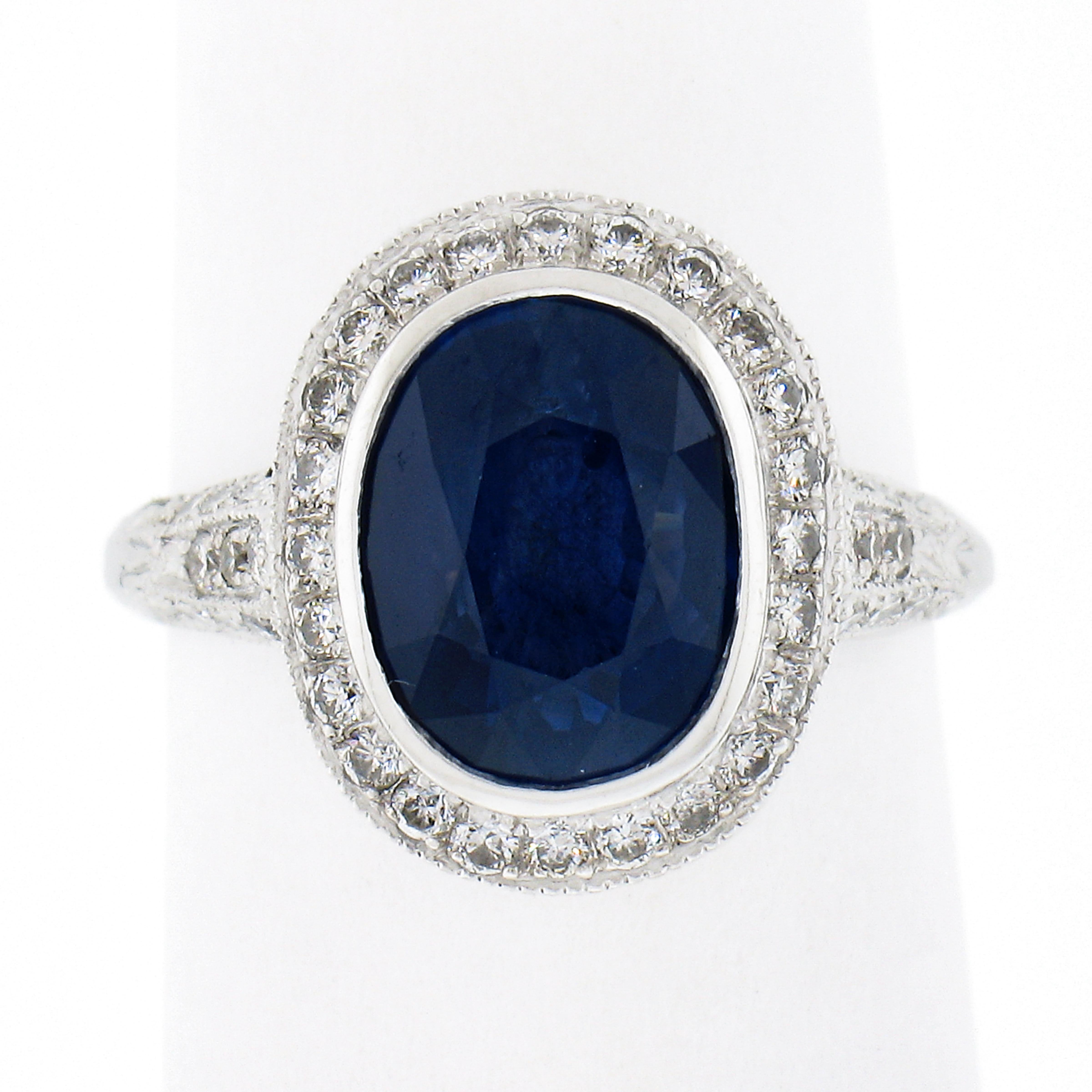 Cette superbe bague en saphir et diamant est réalisée en platine massif et présente un magnifique saphir naturel certifié par le GIA, soigneusement serti au centre d'un halo de diamants en relief. Ce saphir ovale de taille brillant a une couleur