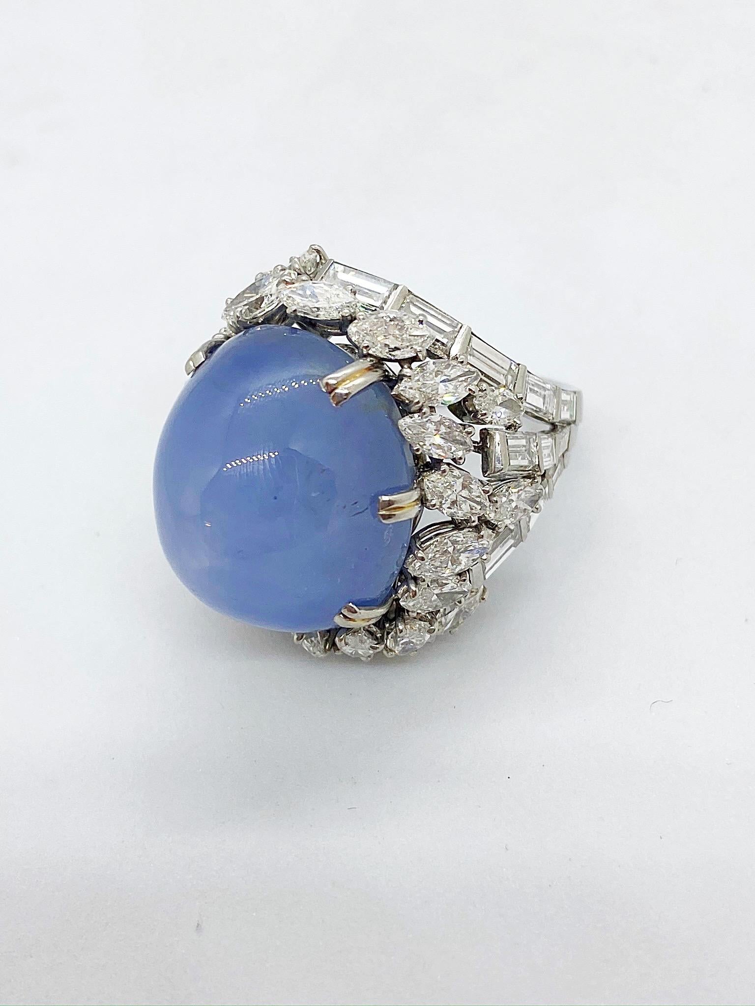 In this cocktail ring a six point star asterism inhabits a glowing denim blue cabochon sapphire. The stars rays are of equal length and reach from the crown of the stone to the base. The fascinating gemstone measures 21.2 x 18.8 x 18 mm and is