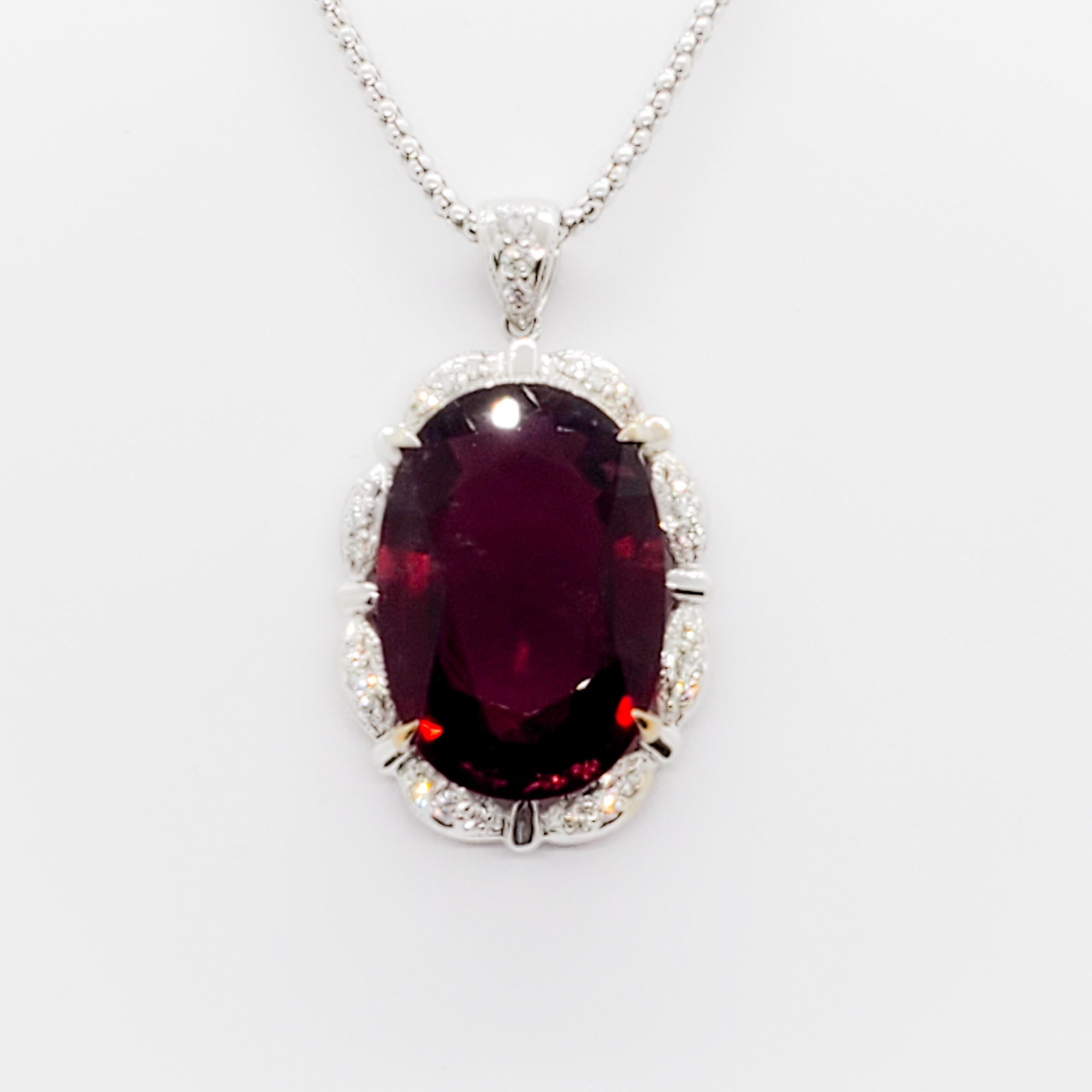 Impressive 28.04 ct rubellite oval with a deep rich red color and 0.53 ct of good quality, white, and bright diamond rounds in a handmade 18k white gold mounting.  Length of chain is 18