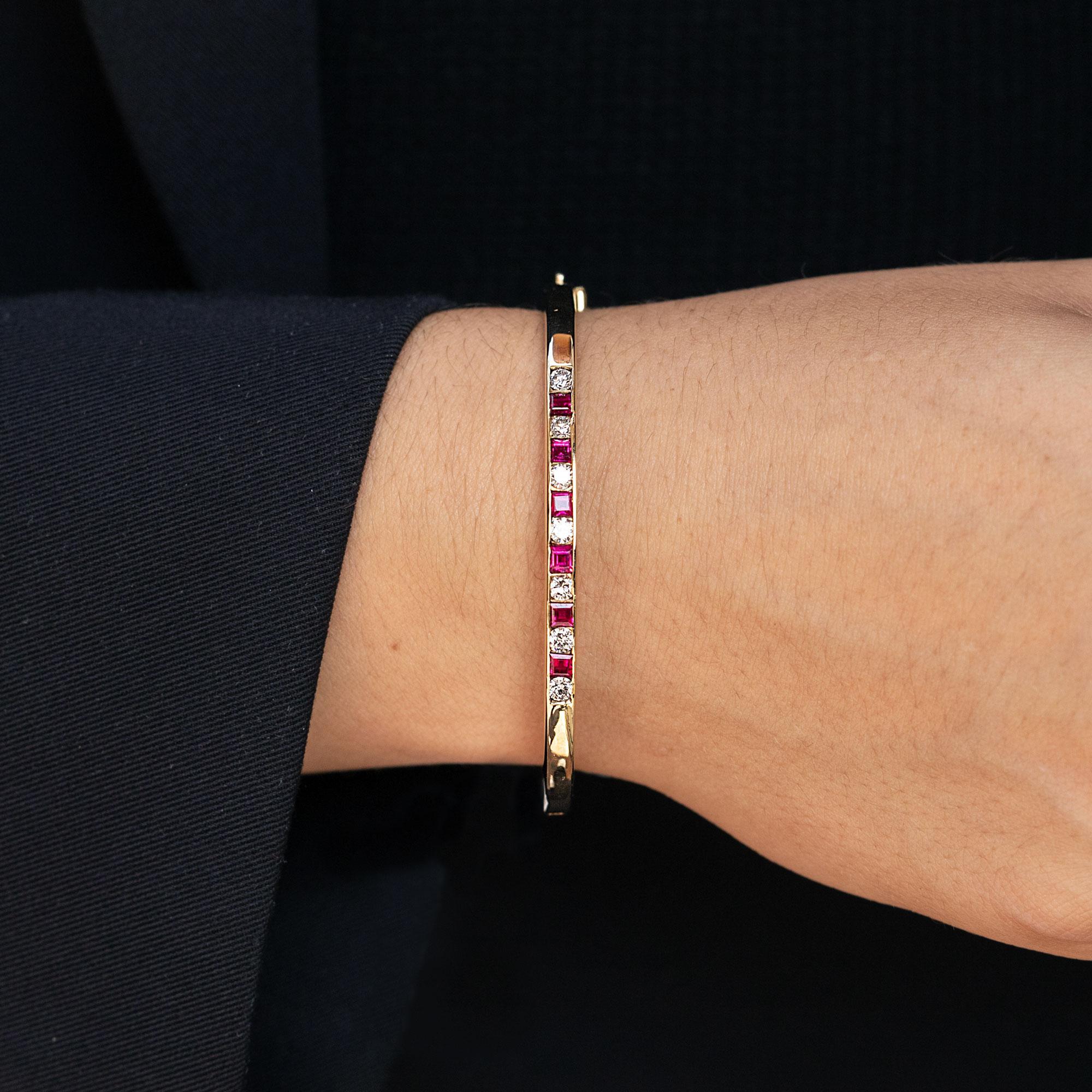 This vintage bangle bracelet is the lovely addition to your estate jewelry collection. Crafted in a classic contemporary 1980s manner, over 1 and a half carats total of vivid, lustrous red natural rubies and fiery diamonds are artfully placed in a