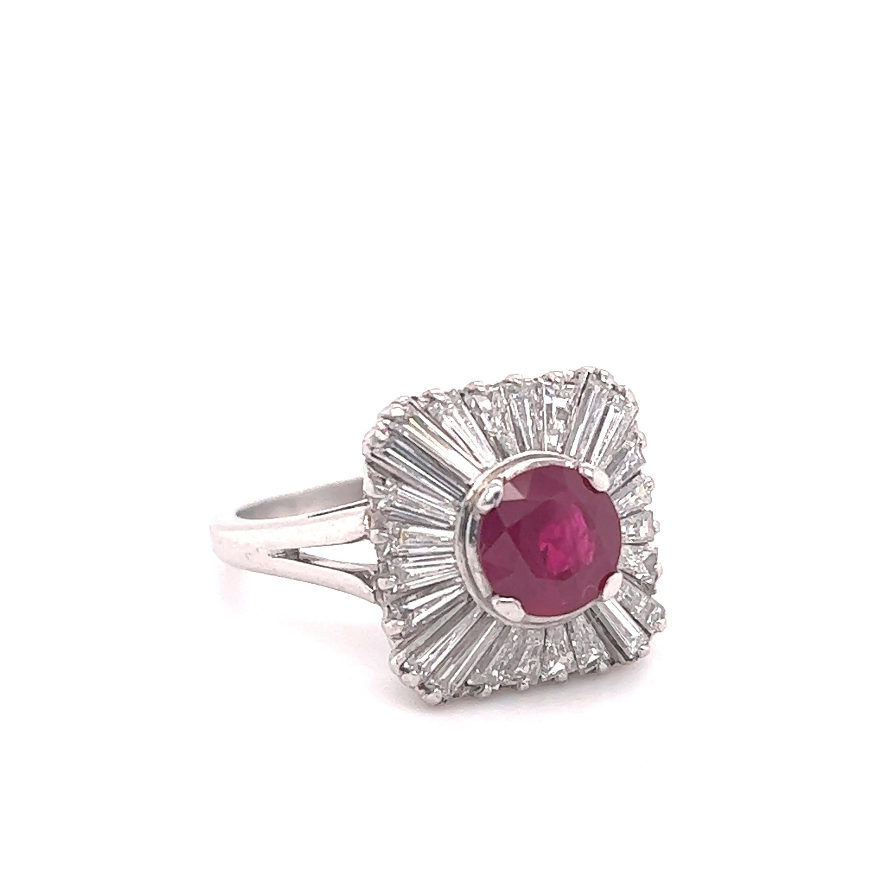 Elegant design seen on this estate masterpiece. This ring is crafted in platinum and shows baguette diamonds and a vibrant red color ruby gemstone. The design of the ring is known as a ballerina ring and is inspired by the shape of a ballerina's