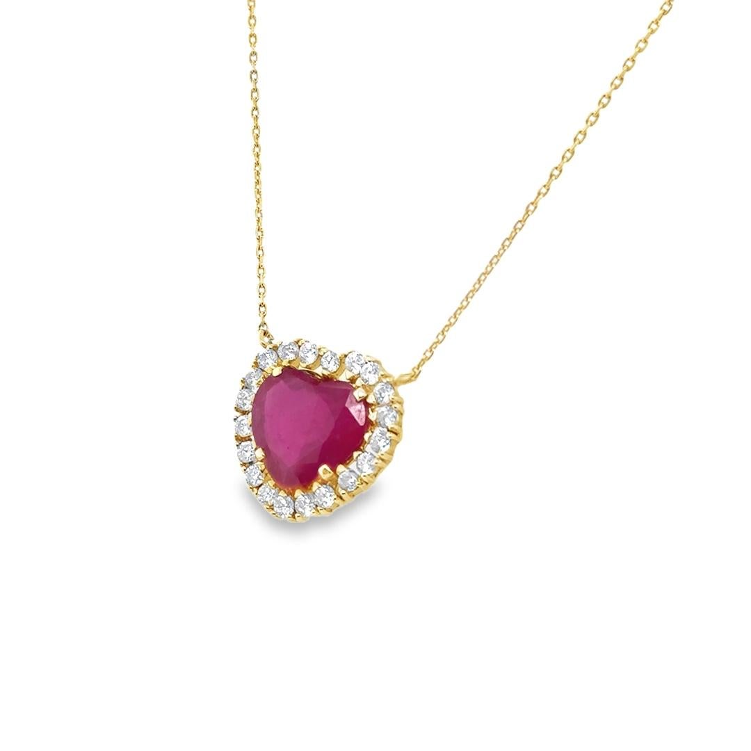 Precioso collar elaborado en oro amarillo de 18 quilates. En el collar destaca una gema de rubí en forma de corazón de color rojo vibrante. El rubí está engastado en un colgante en forma de halo rodeado de veinte diamantes individuales que muestran