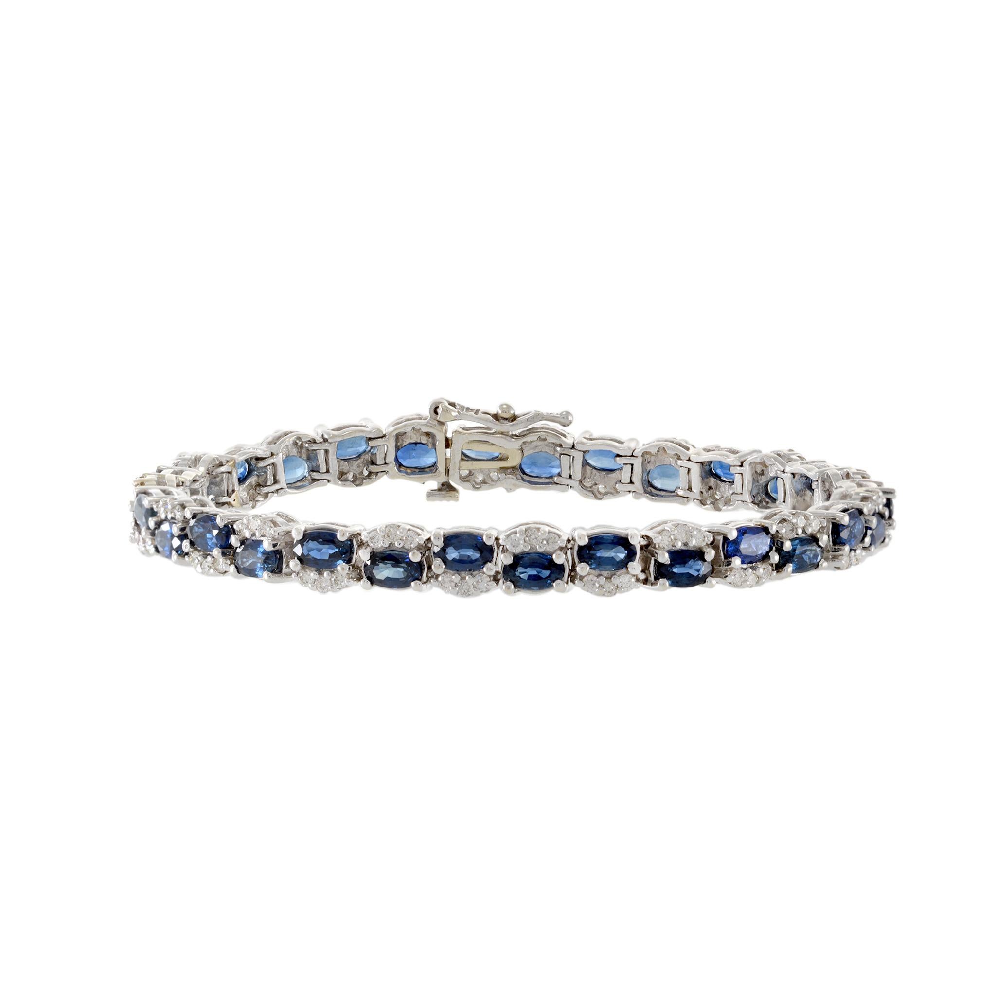 This bracelet is a testament to luxury, crafted from 14kt white gold and a striking combination of genuine blue sapphires and diamonds. The sapphires, each totaling 12.00 carats, are cut in an exquisite oval shape and elegantly alternate with 1.50
