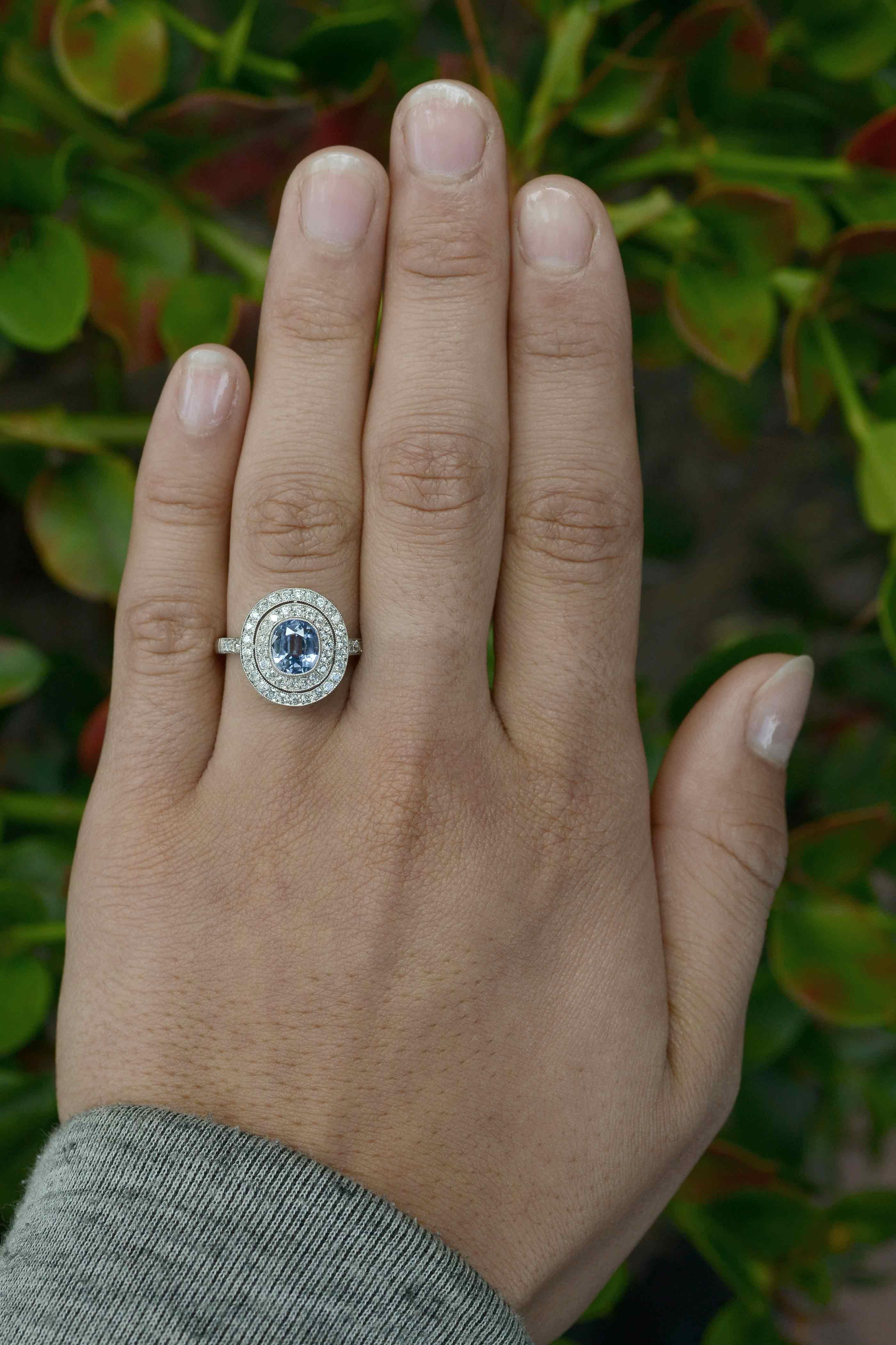 A lovely estate sapphire engagement ring, centered by a a shimmering shade of cornflower blue, the Ceylon sapphire framed by a double diamond halo that adds a brilliant contrast to this heirloom. At a sizable 1.62 carats of captivating luster, and