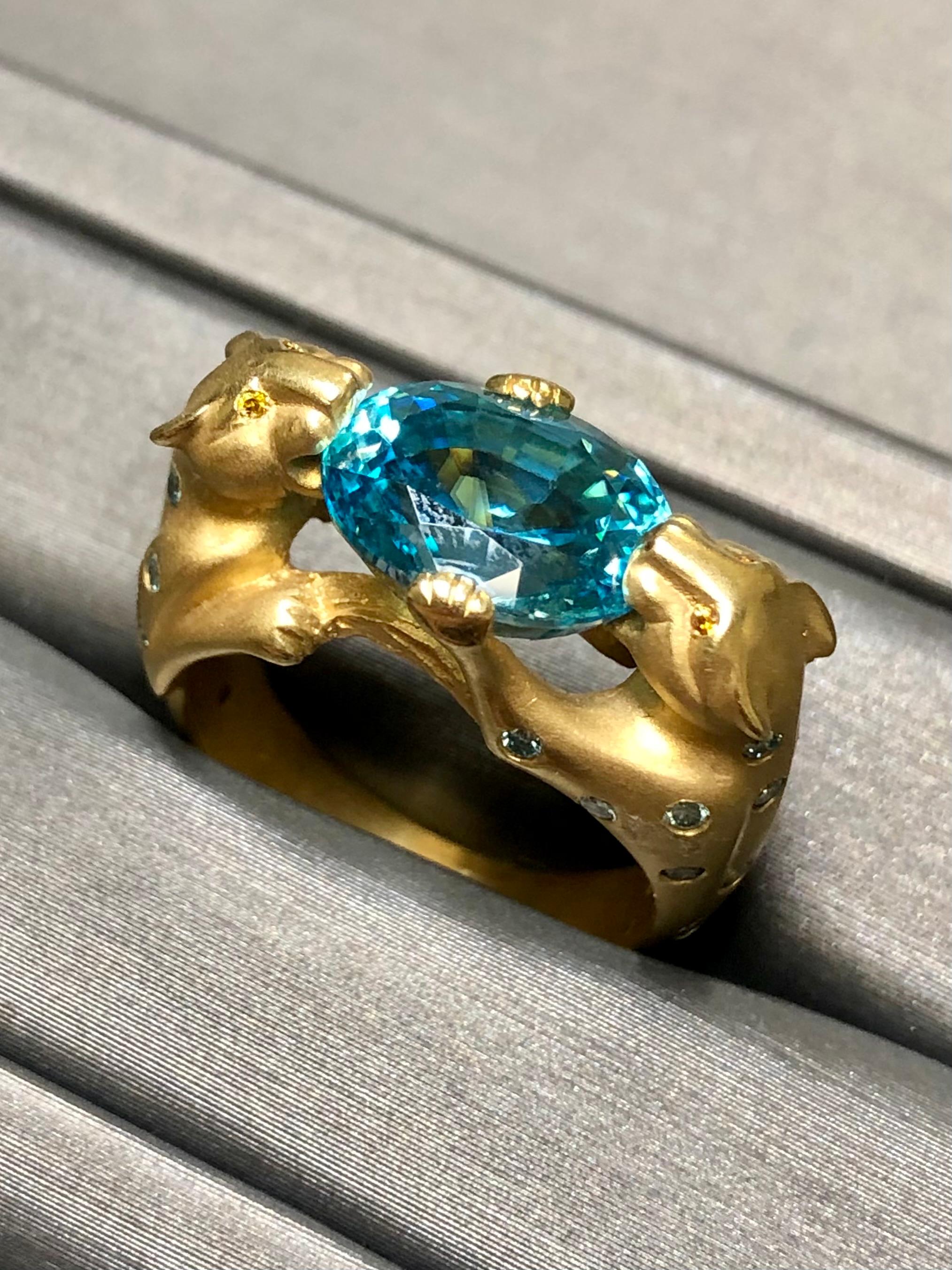 
Undoubtedly one of the highest quality pieces in stock at the moment. This incredible ring has been hand crafted in satin finished 18K yellow gold and held in the mouths of the two panthers is an approximately 7ct deep aqua natural zircon with the