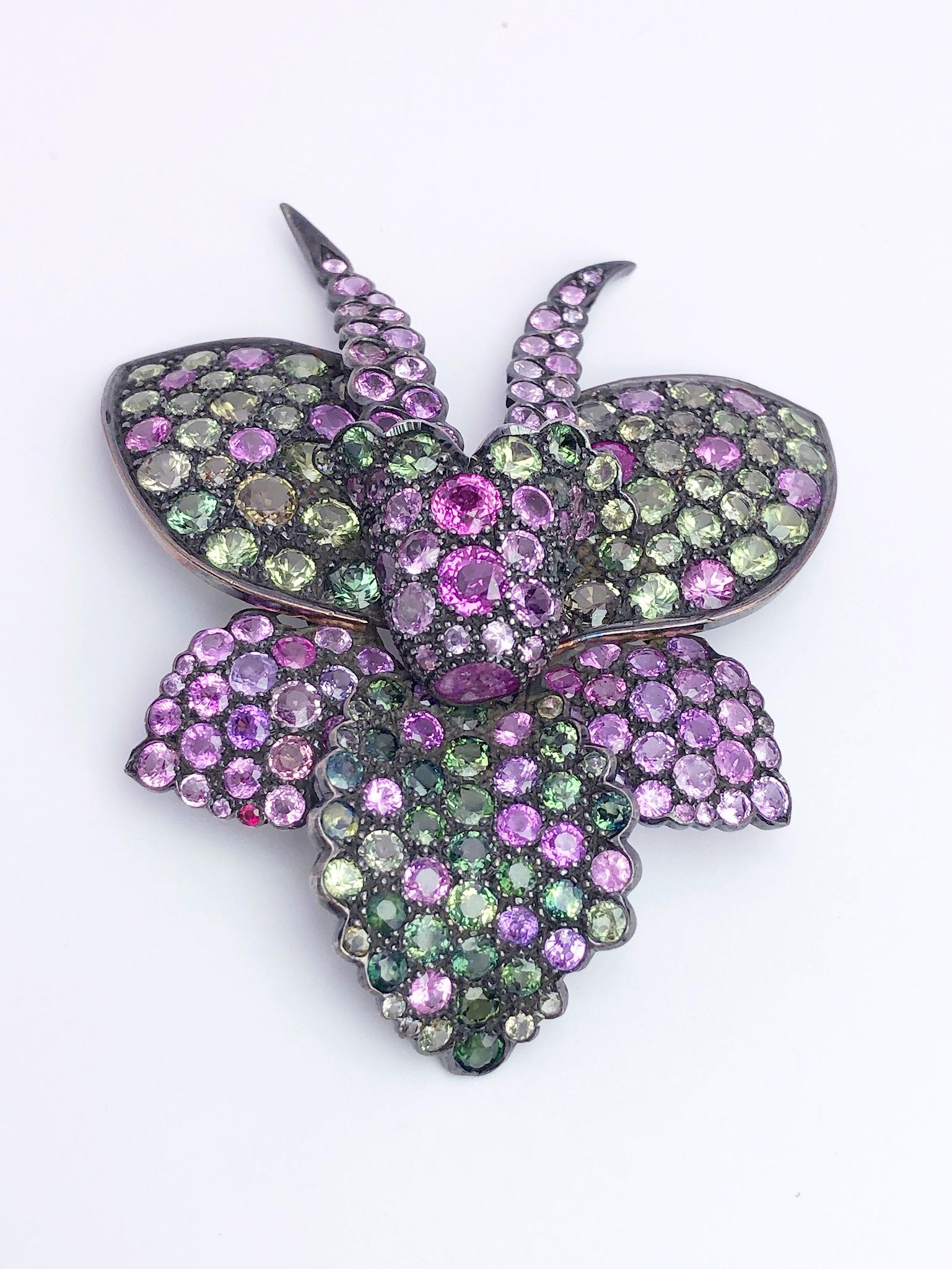 A lovely orchid brooch beautifully set with shades of pink, purple and green sapphires. The combination of prong and bezel settings give depth to the orchid. The brooch measures 3