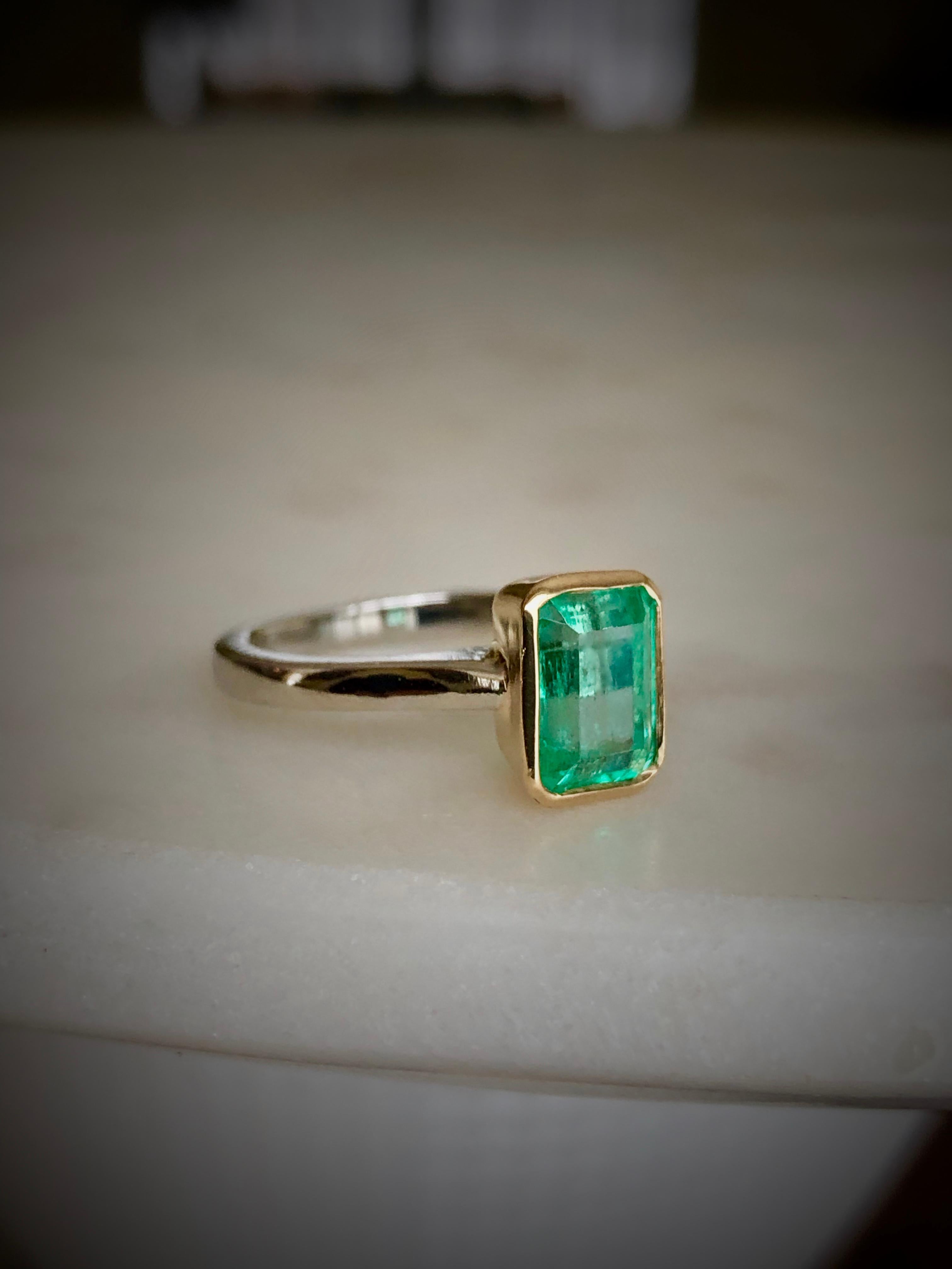 This is an emerald bezel set solitaire estate ring, the center stone is a natural Colombian emerald emerald cut weighting 1.55 carats. Lively medium green, VS clarity.  The engagement solitaire ring is made of solid platinum and yellow 18K. Total