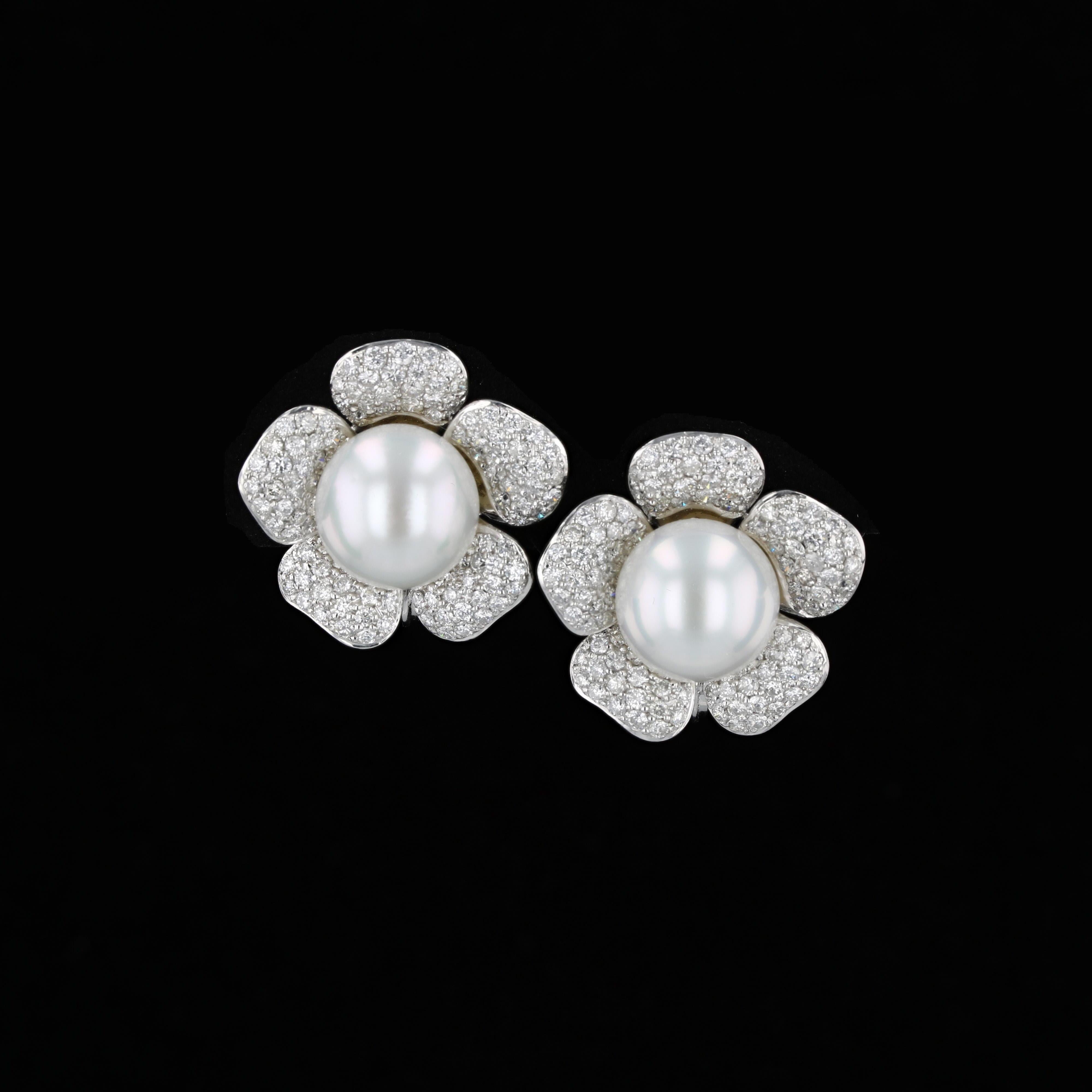 Two 13.50 mm South Sea white pearls center this pair of 18 K white gold flower earrings.  The petals contain 230 round brilliant pave set diamonds weighing approximately 4.83 carats that have an average color of G to H and an average clarity of VS2.