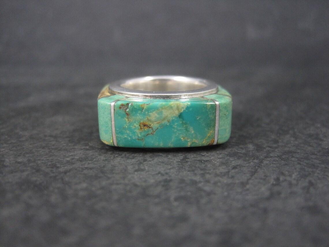 This gorgeous, one of a kind ring is sterling silver with raised turquoise inlay.
It is an older creation from artist Kelly Charveaux.

This ring measures 3/8 of an inch wide and 1/4 of an inch at its thickest.
Size: 5
Weight: 12.6 grams

Marks: