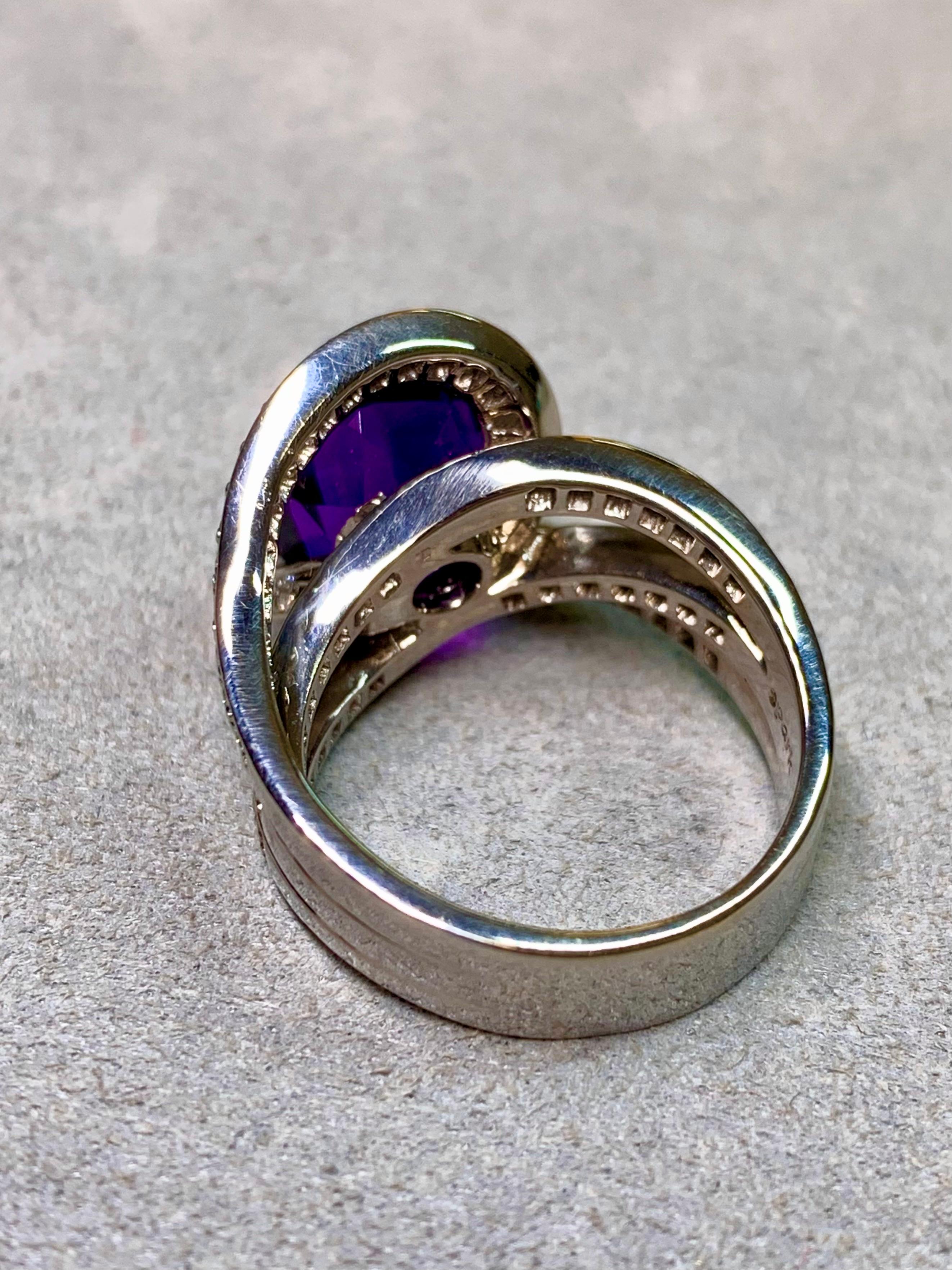 
Ein kühner und moderner Cocktailring von Spark Creations mit einem dramatischen natürlichen Amethysten im Fantasieschliff von außergewöhnlicher Lebendigkeit. Der reich gesättigte violette Edelstein wird von drei fließenden Bändern aus 18-karätigem