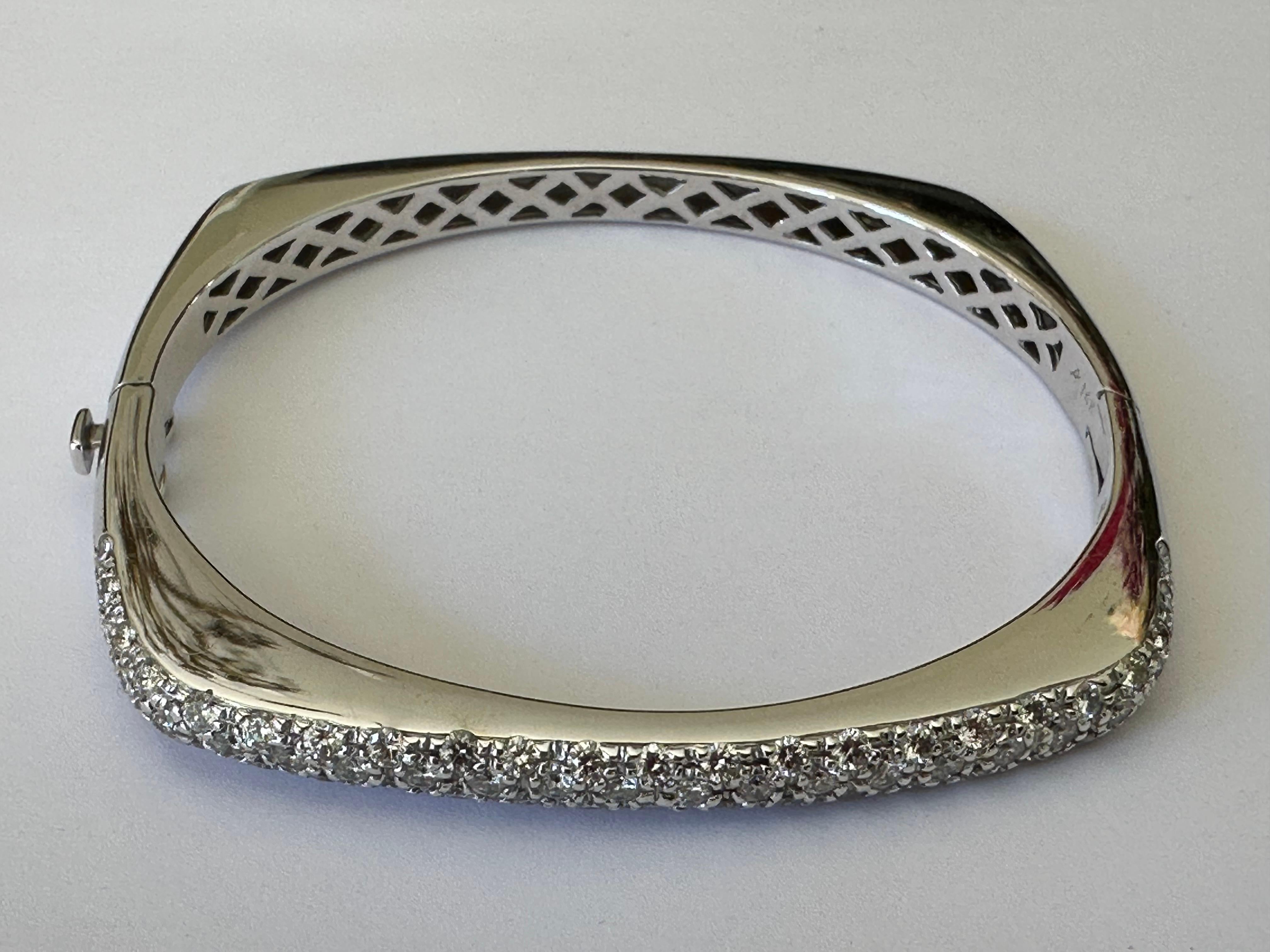 A cluster of round brilliant-cut diamonds together totaling approximately 2.50 carats, IJ color VS clarity, shine across the top of this Estate square-shaped bangle bracelet crafted in 14K white gold. Maker's mark AK. The bangle measures 7 inches.