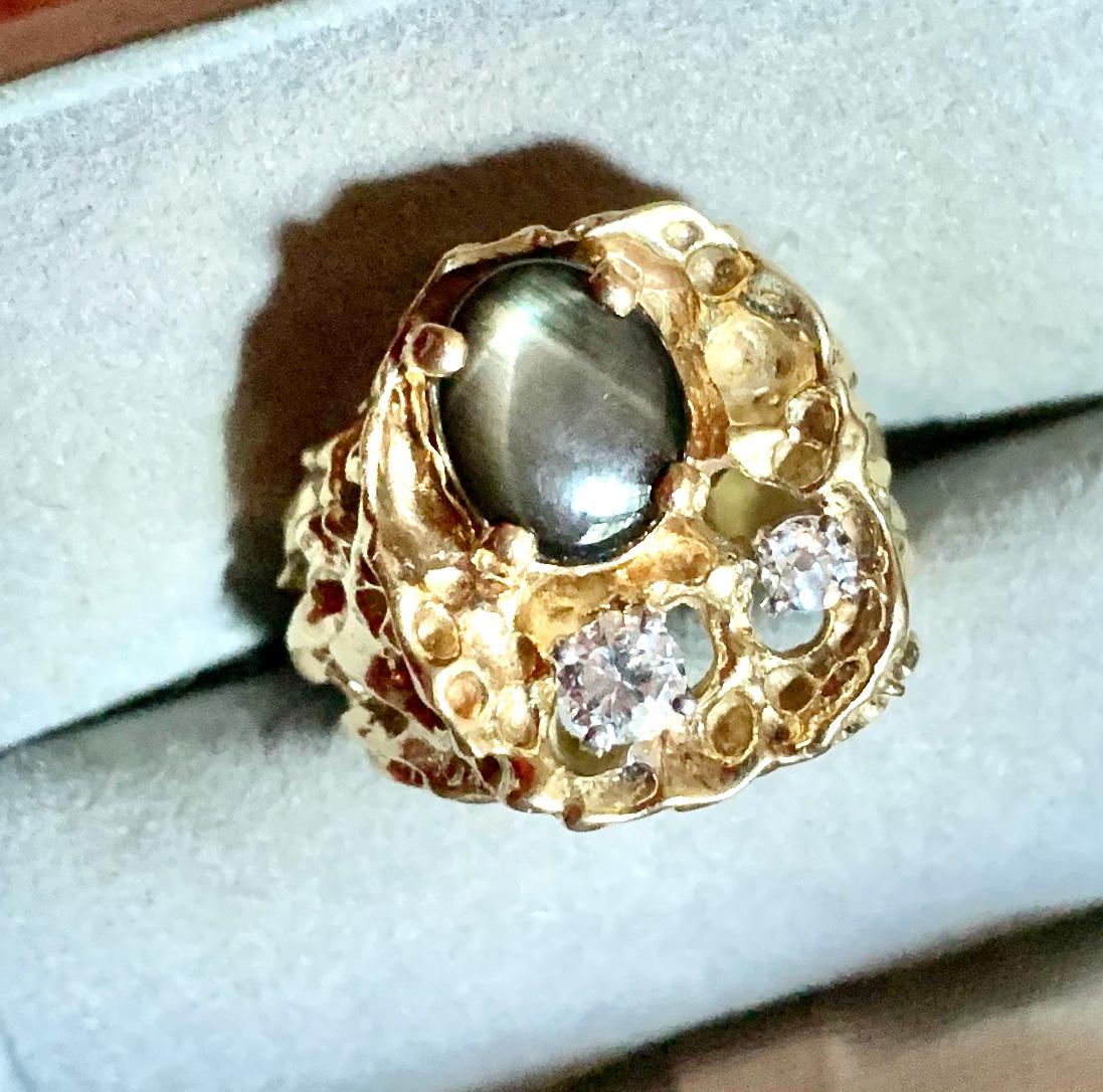 Substantial 1970's Modernist ring very reminiscent of the designs of Arthur King, with an oval black star sapphire measuring 9mm by 7mm and two diamonds, .35 and .15 carat, G/H VS/SI.
Elvis Presley owned a very similar 1970's black star sapphire and