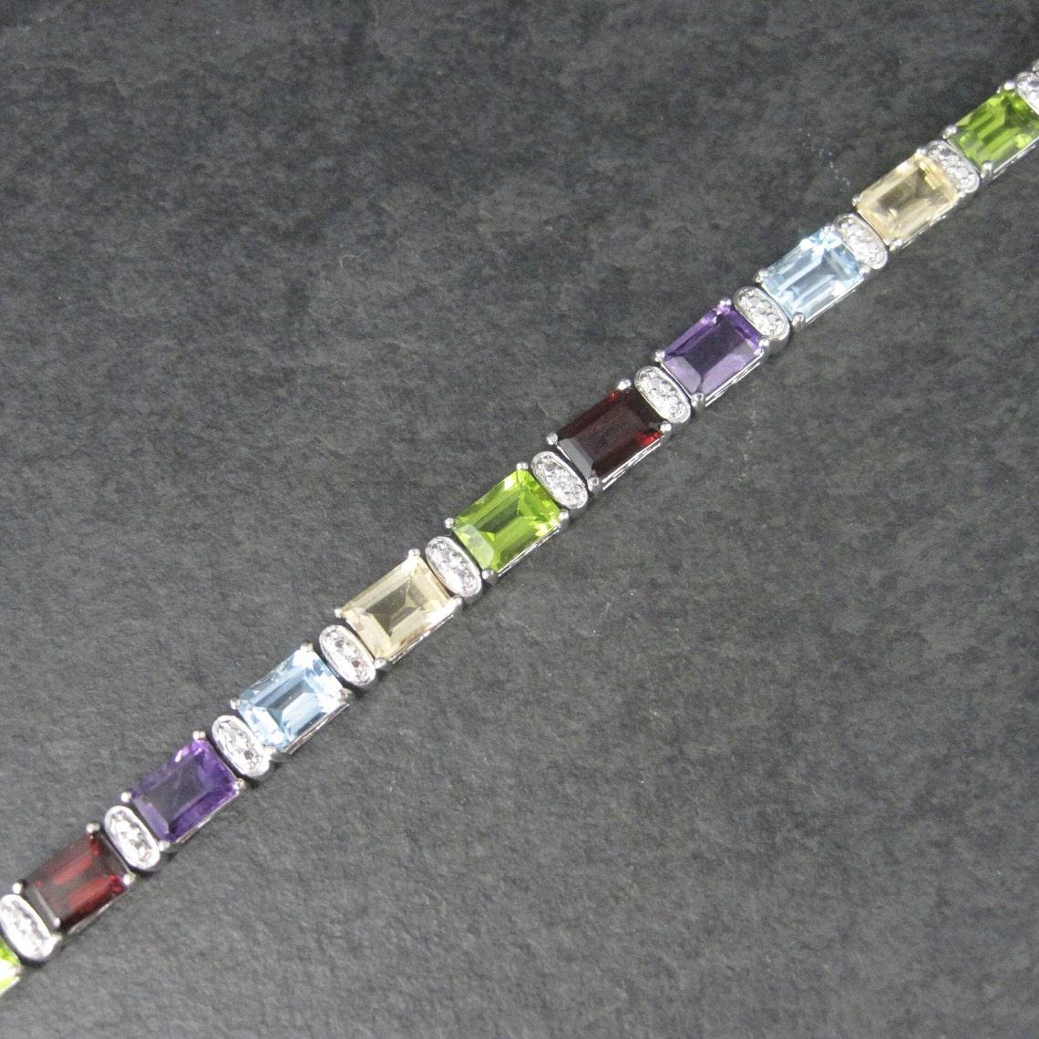 Dieses wunderschöne Tennisarmband ist aus Sterlingsilber.
Er besteht aus 5x7 mm großen Granaten, Zitrinen, Peridot, Amethysten und Topas und ist ein Produkt von Ross Simons.

Abmessungen: 1/4 von einem Zoll breit, 7 1/2 tragbare Zoll

Zustand:
