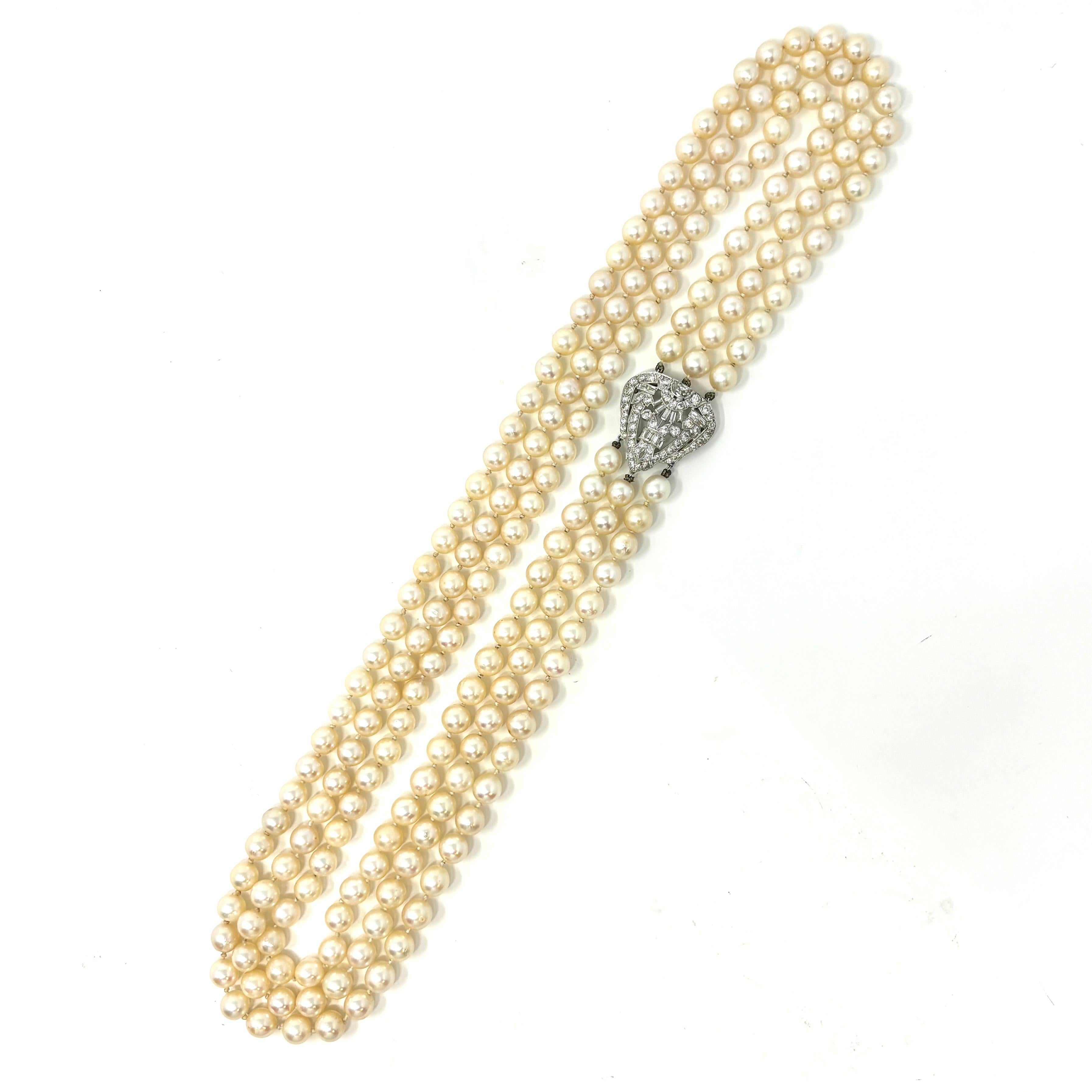 An elegant three strand Akoya pearl necklace with a platinum ornament containing approximately 3 carats total weight of round brilliant, baguette and half moon cut diamonds. The cream colored pearls are 7.5-8.5 mm, and the longest strand is 24
