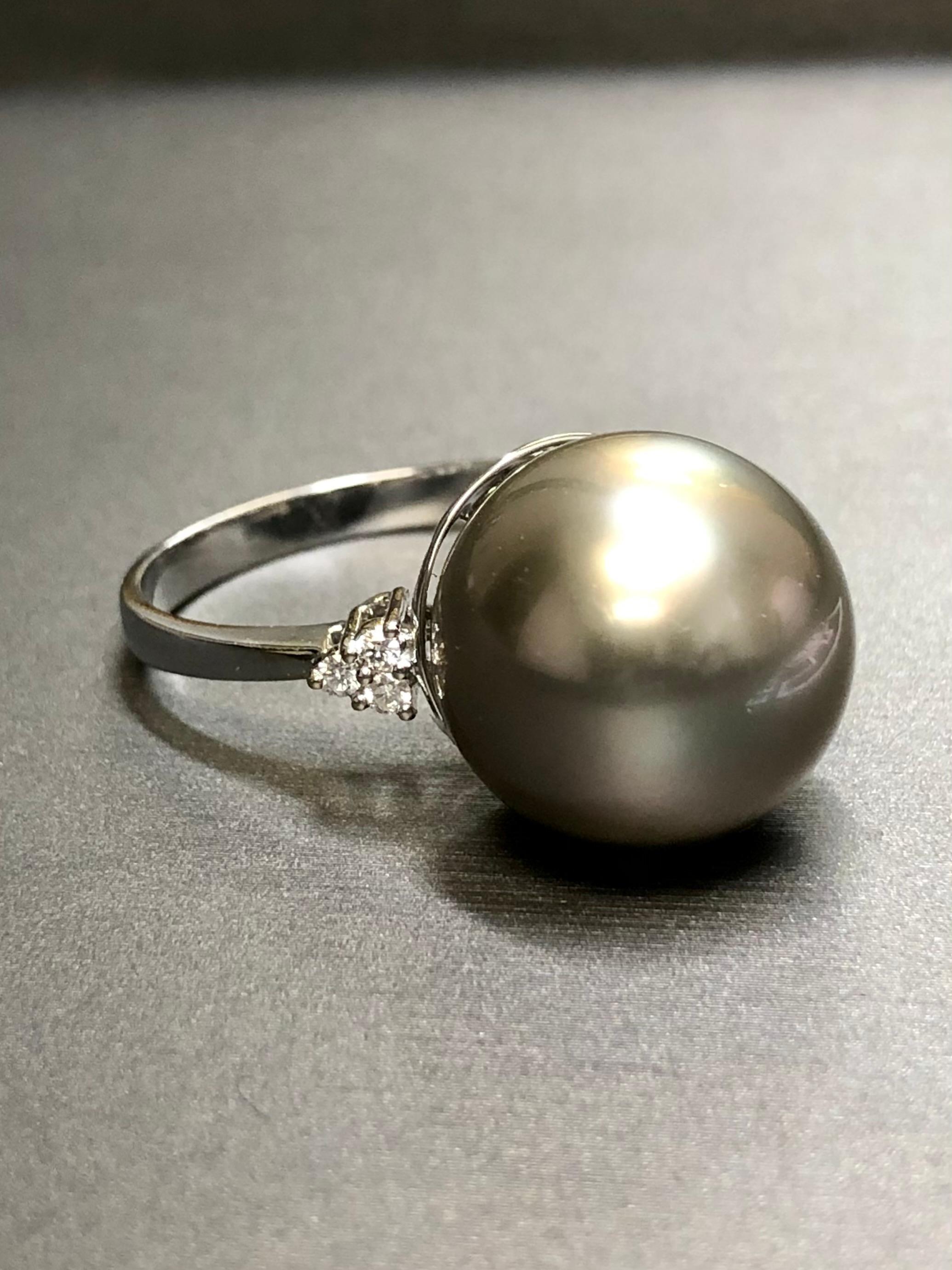 This beautiful vintage ring is centered by an impressive 16mm Tahitian pearl completely free of pitting or blemishes with a gorgeous even silver gray luster. Flanking the pearl is .12cttw in F-G Vs1 clarity round
