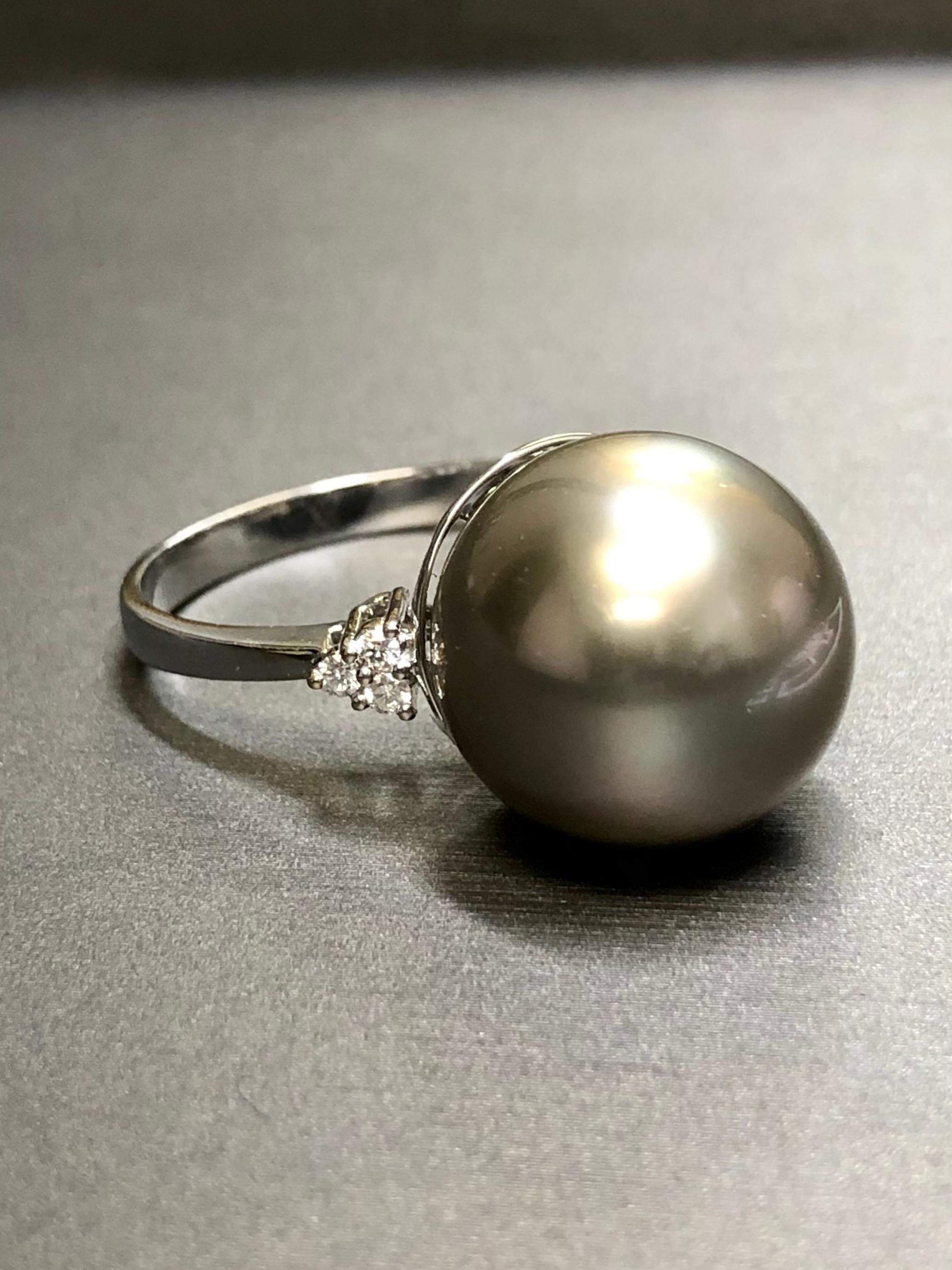 Dieser wunderschöne Vintage-Ring wird von einer beeindruckenden 16 mm großen Tahiti-Perle zentriert, die völlig frei von Grübchen oder Makeln ist und einen wunderschönen, gleichmäßigen silbergrauen Glanz hat. Flankiert wird die Perle von runden