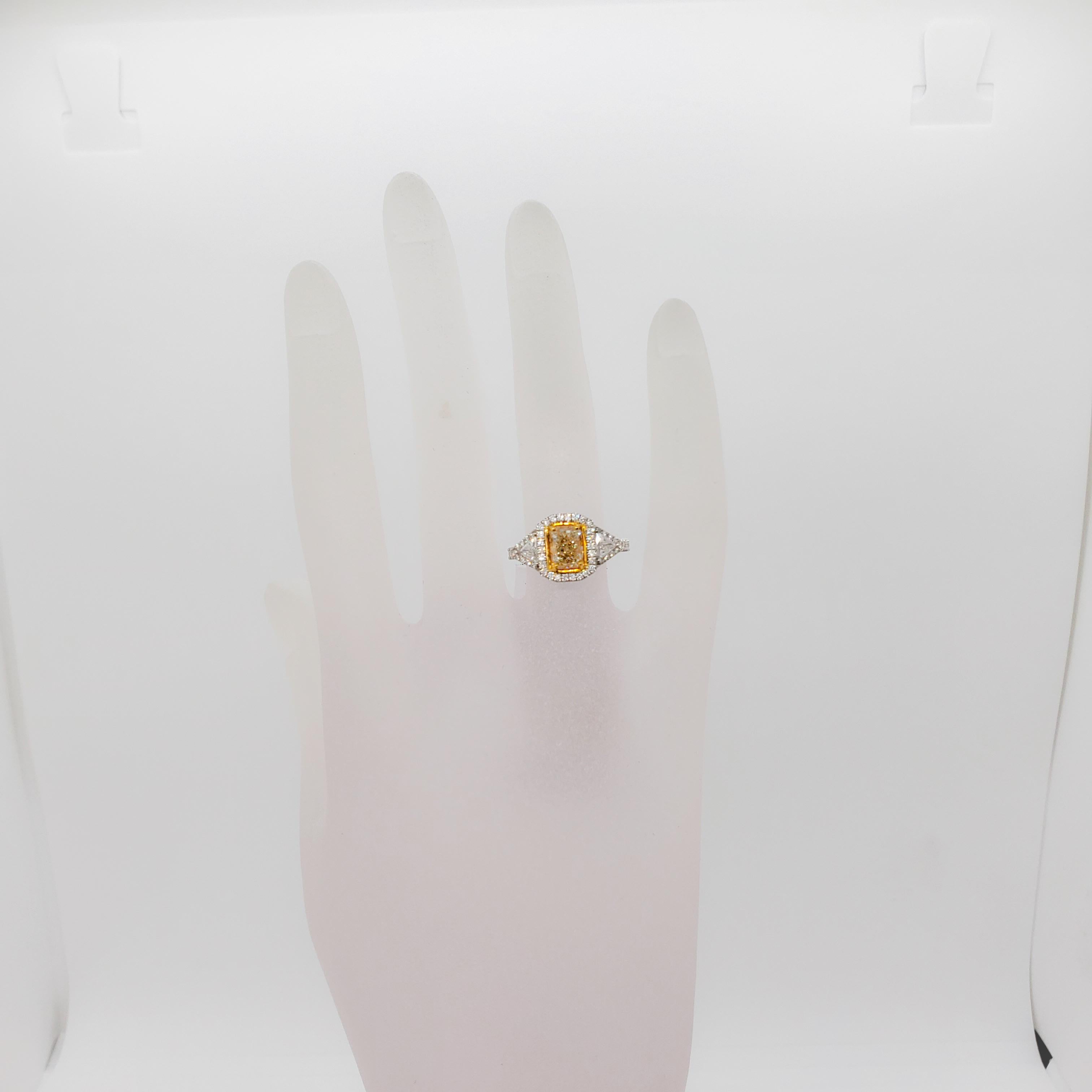 Gorgeous estate ring featuring a 1.57 ct. natural yellow diamond radiant and 0.87 ct. of good quality white, and bright diamond rounds and trillions.  Handmade 18k white and yellow gold mounting.  Ring size 6.5.  Mint condition.  