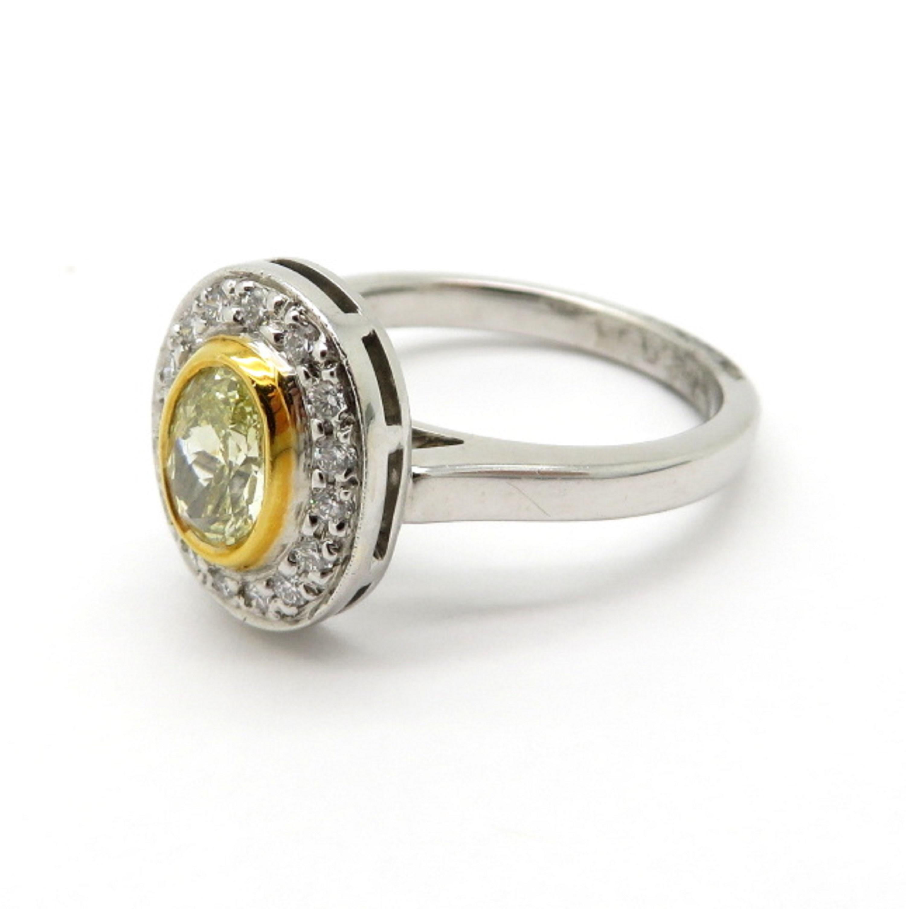 Estate yellow oval diamond halo 18K and platinum ring. Showcasing one oval brilliant cut fancy yellow diamond framed in 18K yellow gold having VS1 clarity grade weighing approximately 0.66 carats. Interspersed with 18 round brilliant cut diamonds