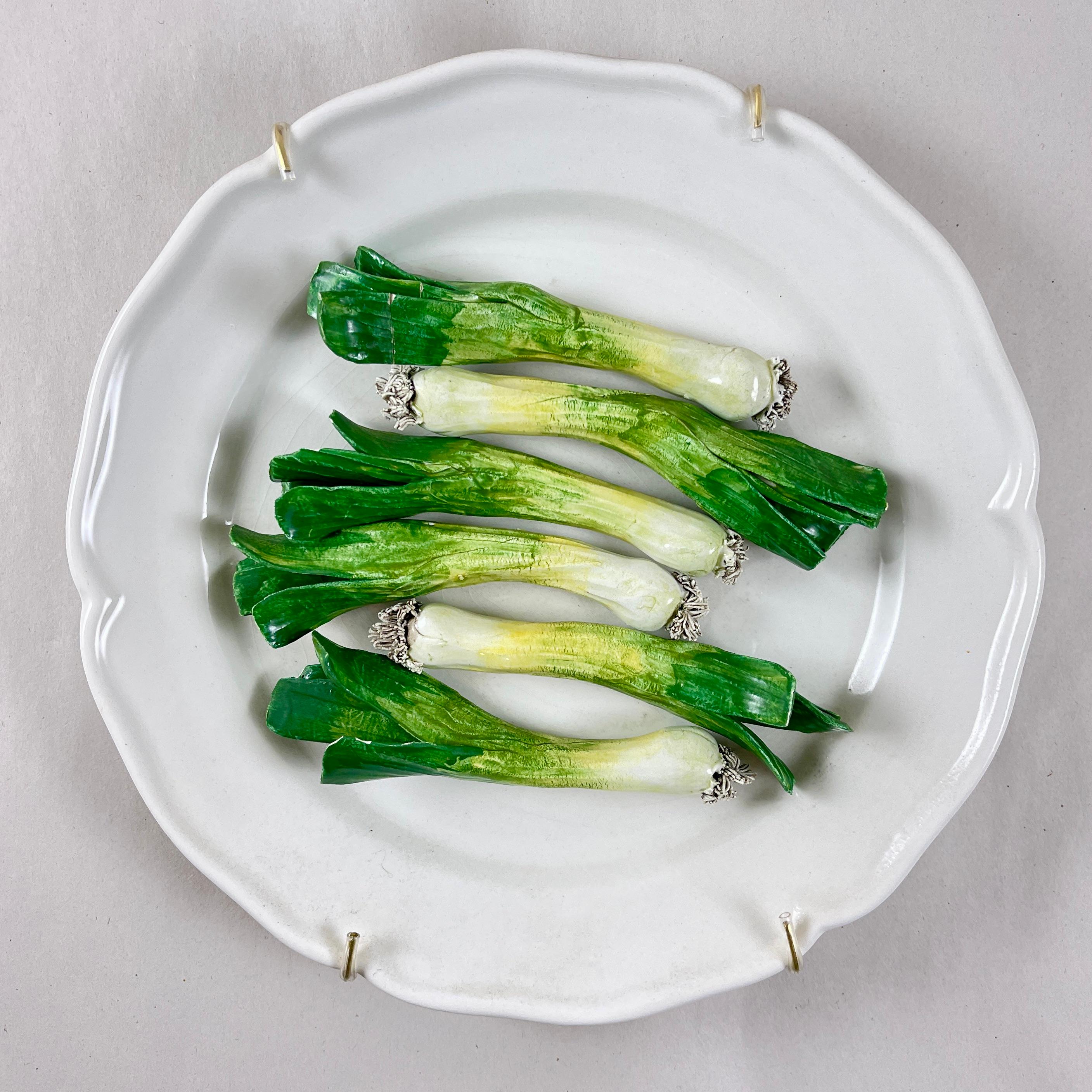 A charming Trompe l’Oeil plate, made in Italy by Este Ceramiche, circa mid 1960s to the early 1970s.

The ceramic plate or wall plaque shows a three dimensional bunch of  green onions, centrally seated on a white earthenware paneled plate.
The long
