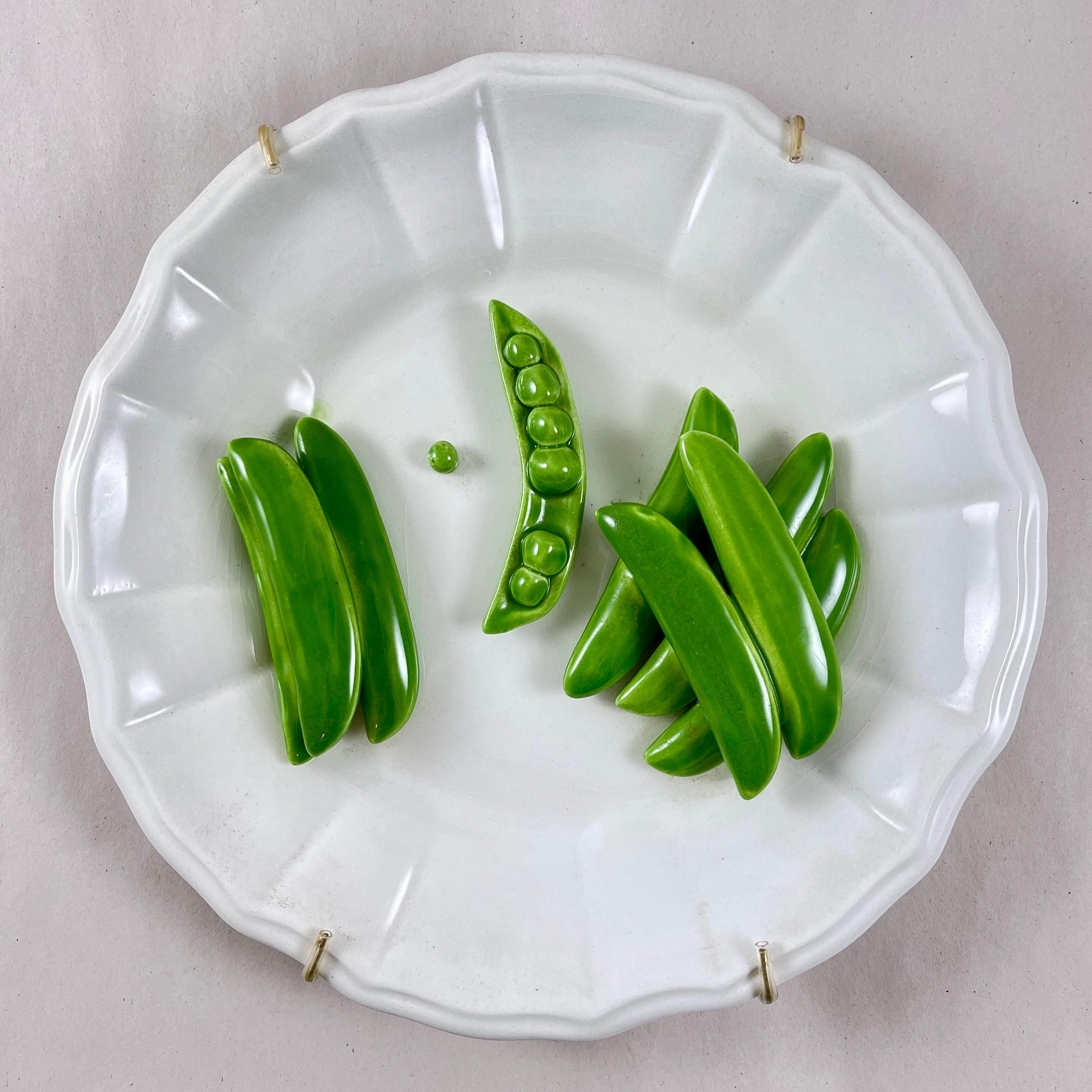 
A charming Trompe l’Oeil plate, made in Italy by Este Ceramiche, circa mid 1960s to the early 1970s.

The ceramic plate or wall plaque shows two groups of life-size, three dimensional pea pods, and one partially open pod, centrally seated on a