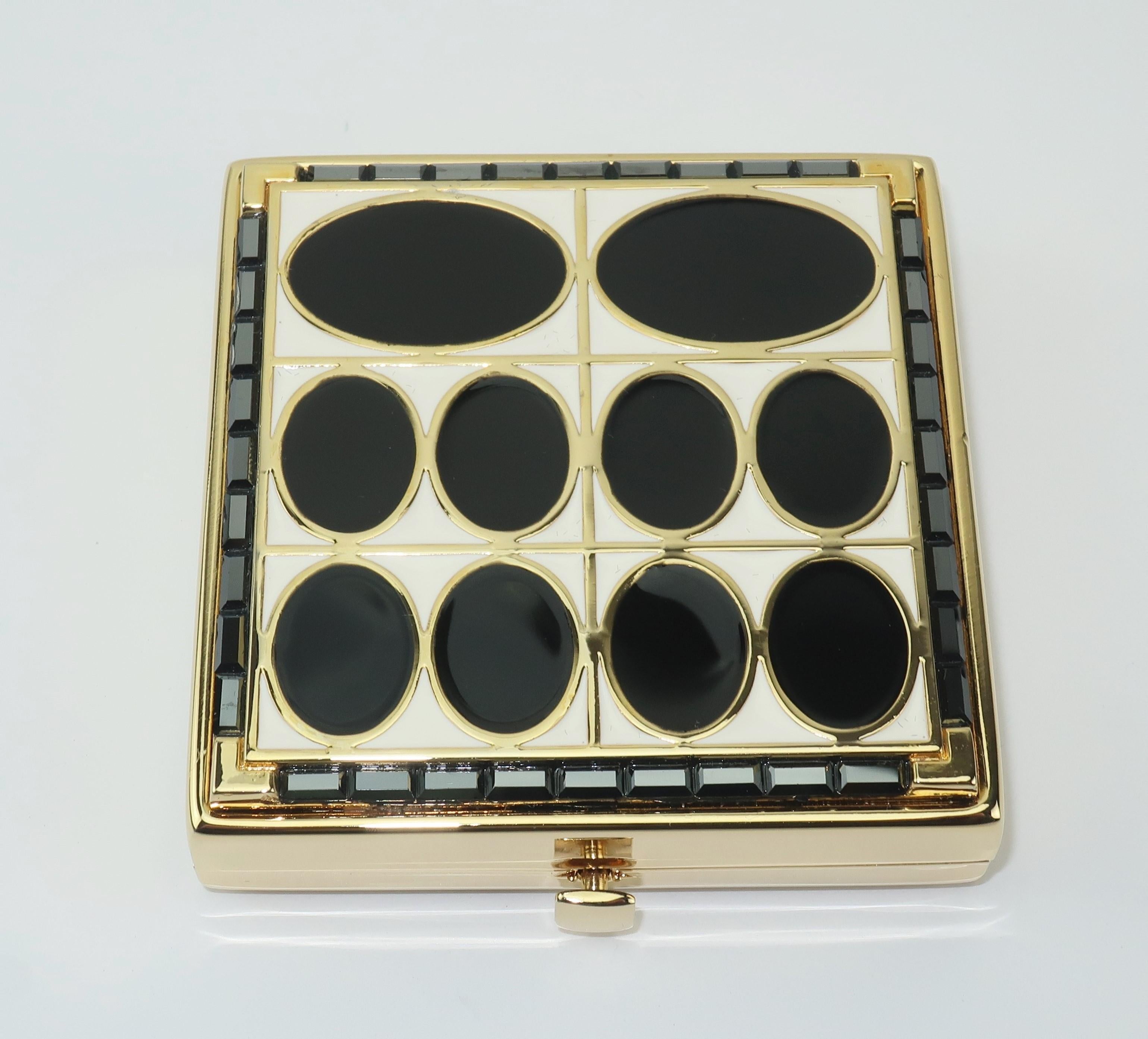 A collectible powder compact from Estee Lauder with an Art Deco motif in black and white enamel accented with black (almost gunmetal) rhinestones in a jewelry quality gold tone metal.  The push button closure opens to reveal a mirror and a