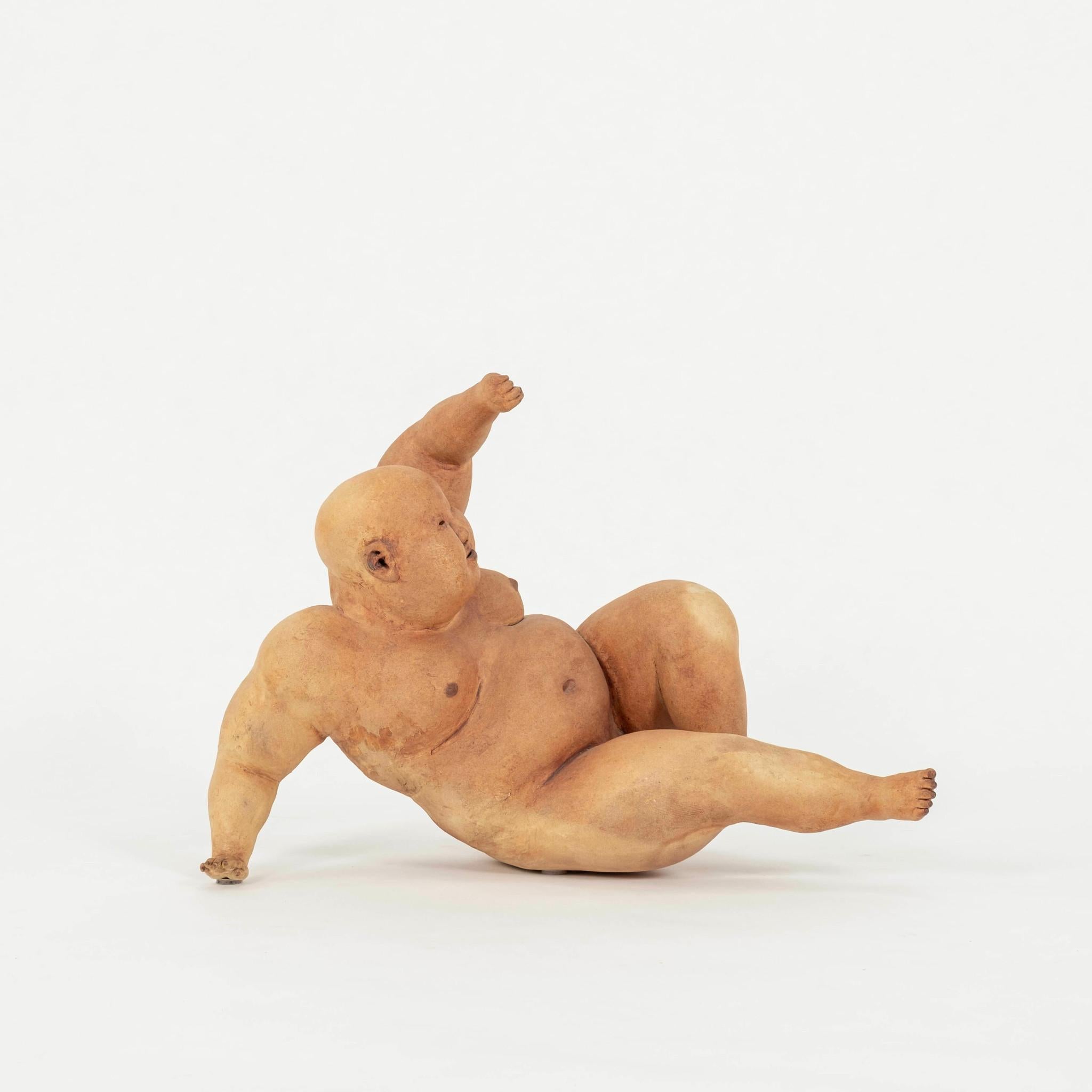 Escultura masculina calva y fornida de Esther Shimazu. Utiliza técnicas artesanales para construir figuras de arcilla utilizando engobes coloreados, óxidos al cocerlos, luego los lija a mano y frota con pigmentos para crear una sensación de volumen